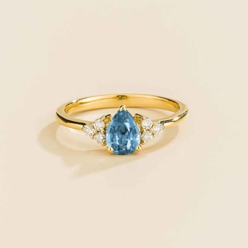 Juvetti yellow gold ring featuring a pear-cut lab-grown aquamarine with lab-grown diamond side stones.