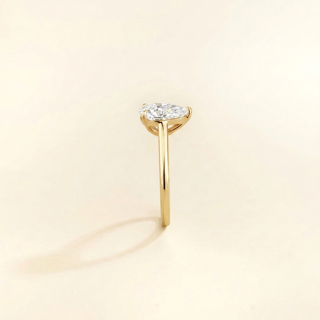Solitaire engagement ring with a 2 carat pear-cut diamond in a three-prong cathedral setting on a slim polished yellow gold band.