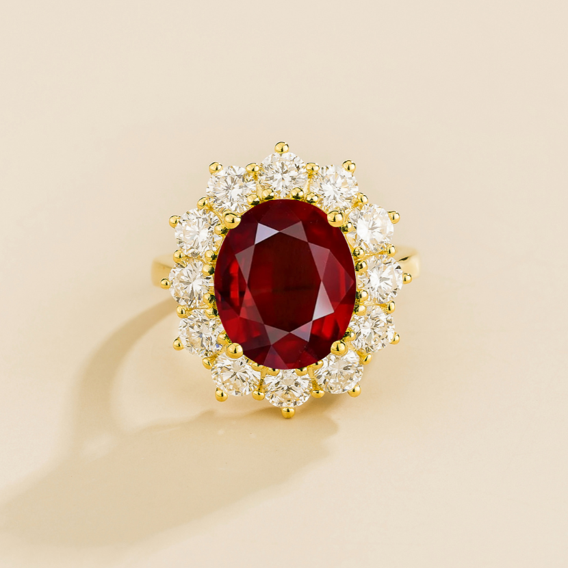 Gold ring with large oval ruby gemstone with diamonds halo on a beige background