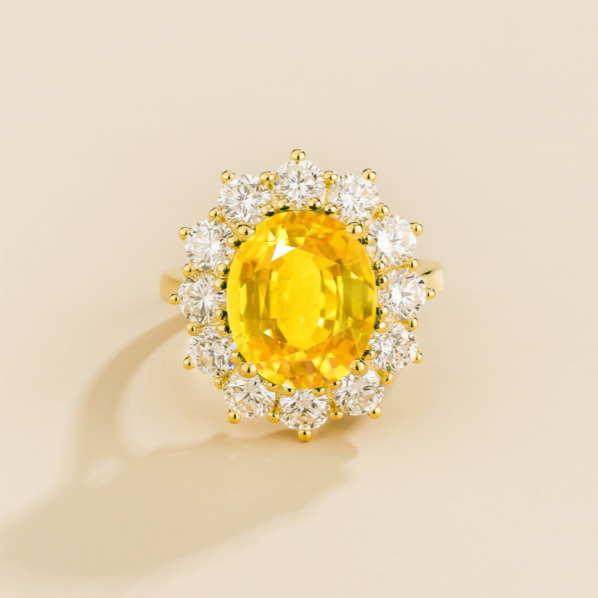 Juvetti yellow gold halo ring featuring an oval lab-grown yellow sapphire surrounded by round lab-grown diamonds.