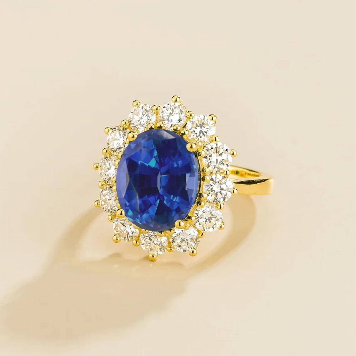 Gold ring with a oval blue gemstone and diamond halo accents on a beige background