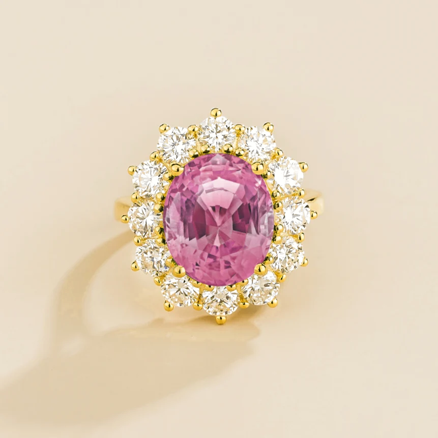 Juvetti yellow gold halo ring featuring an oval lab-grown pink sapphire surrounded by round lab-grown diamonds.
