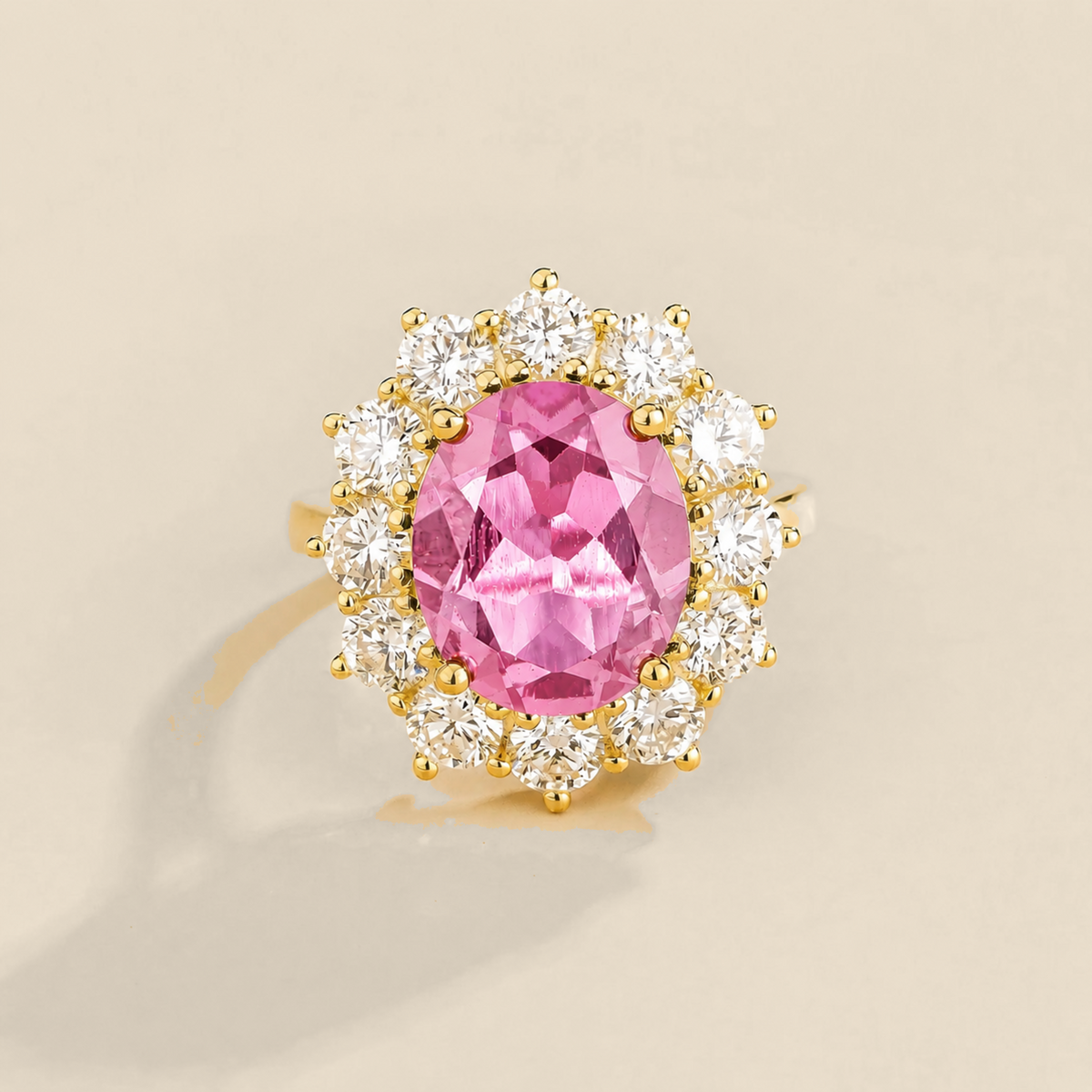 Juvetti yellow gold halo ring featuring an oval lab-grown pink sapphire surrounded by round lab-grown diamonds.