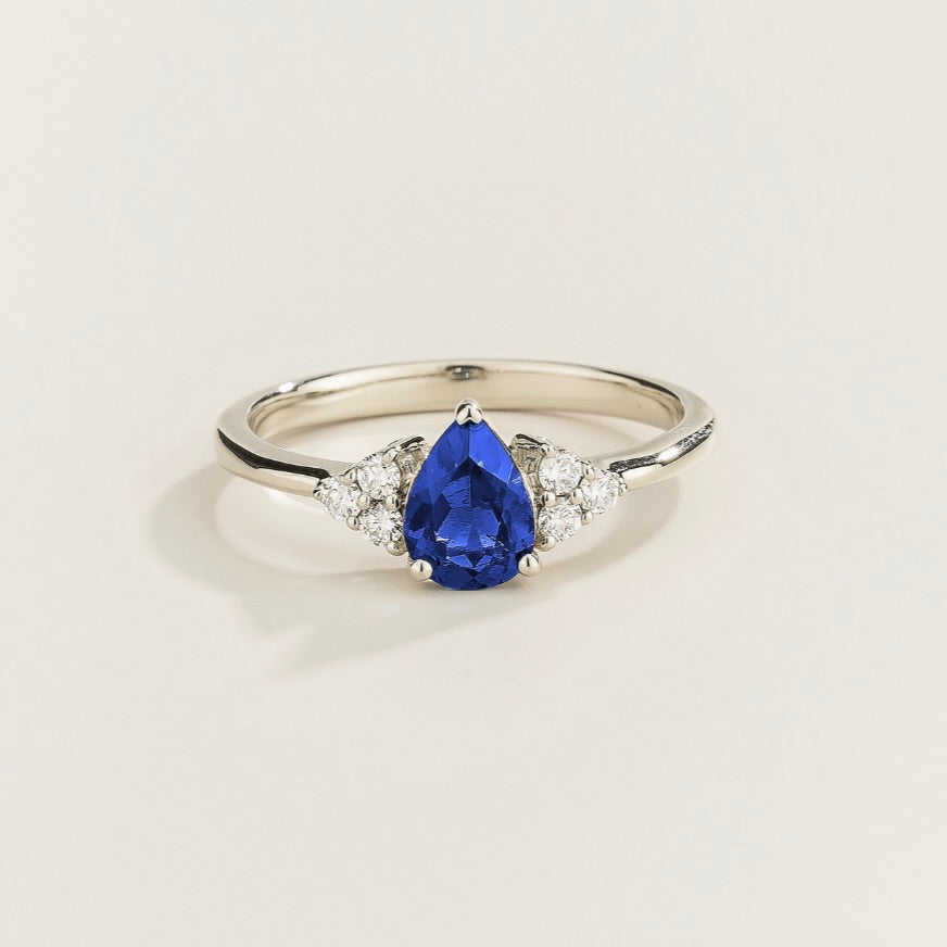 Juvetti white gold ring featuring a pear-cut lab-grown royal blue sapphire with lab-grown diamond side stones.
