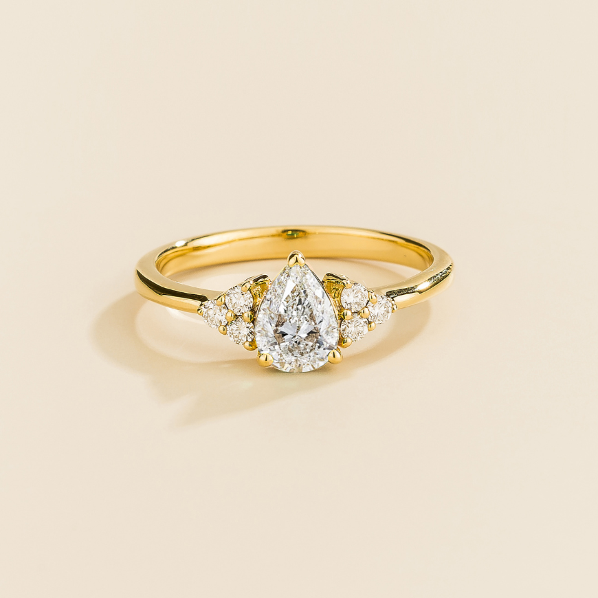 Juvetti yellow gold ring featuring a pear-cut lab-grown diamond with lab-grown diamond side stones.