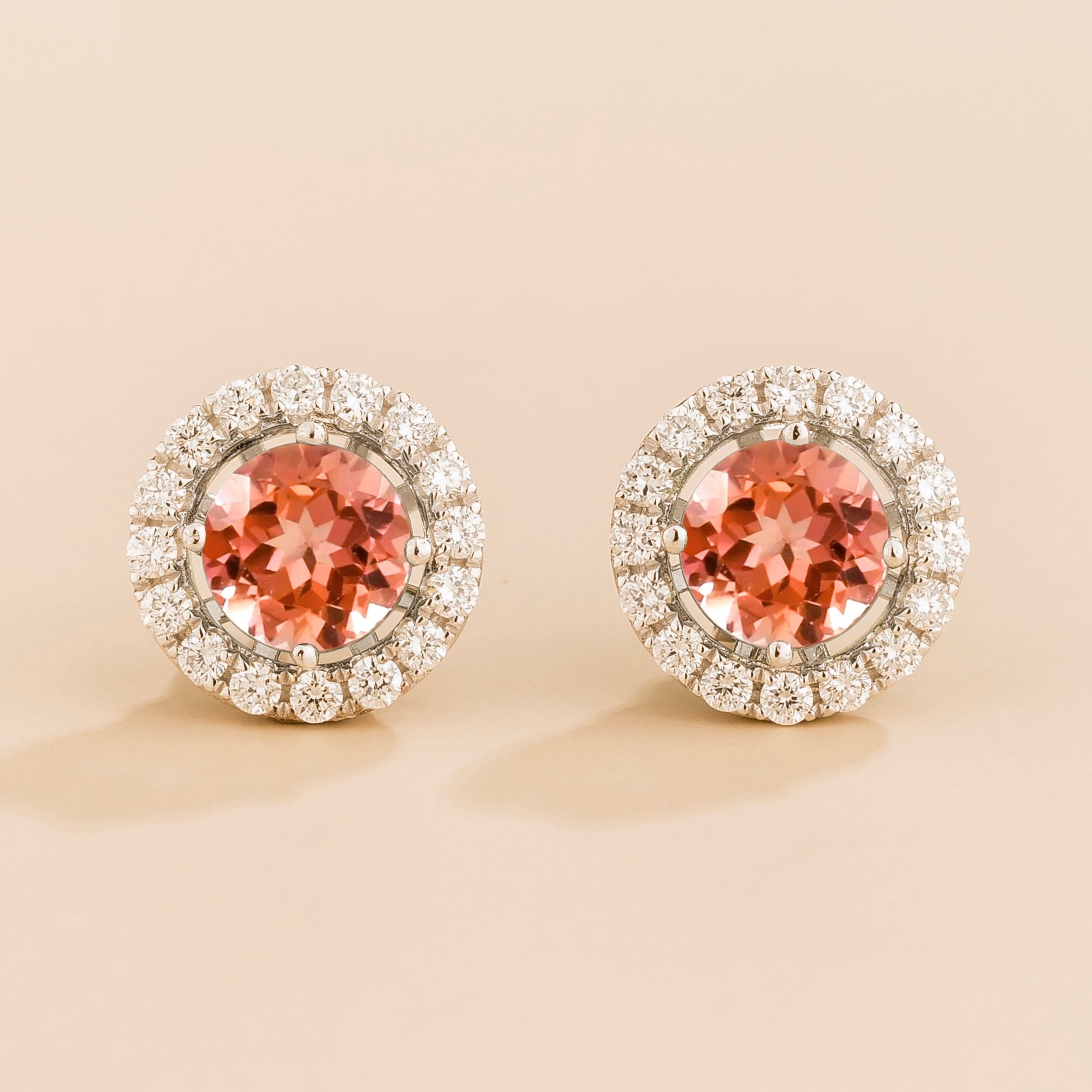 A pair of white gold floret earrings set with round padparadscha sapphire centerpiece and surrounding round diamonds halo. Removable halo piece.