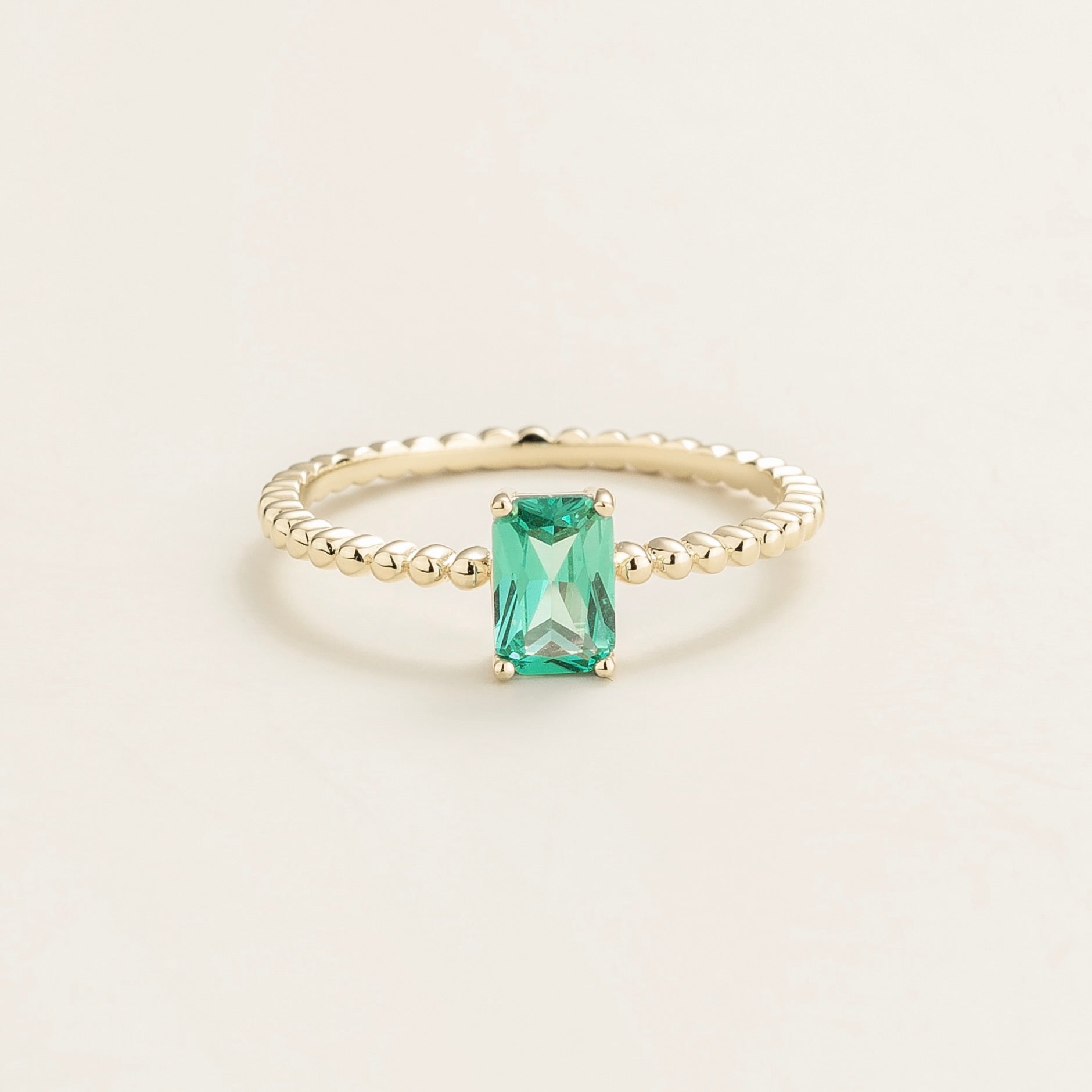 Juvetti white gold ring featuring an emerald-cut lab-grown paraiba gemstone on a beaded band.