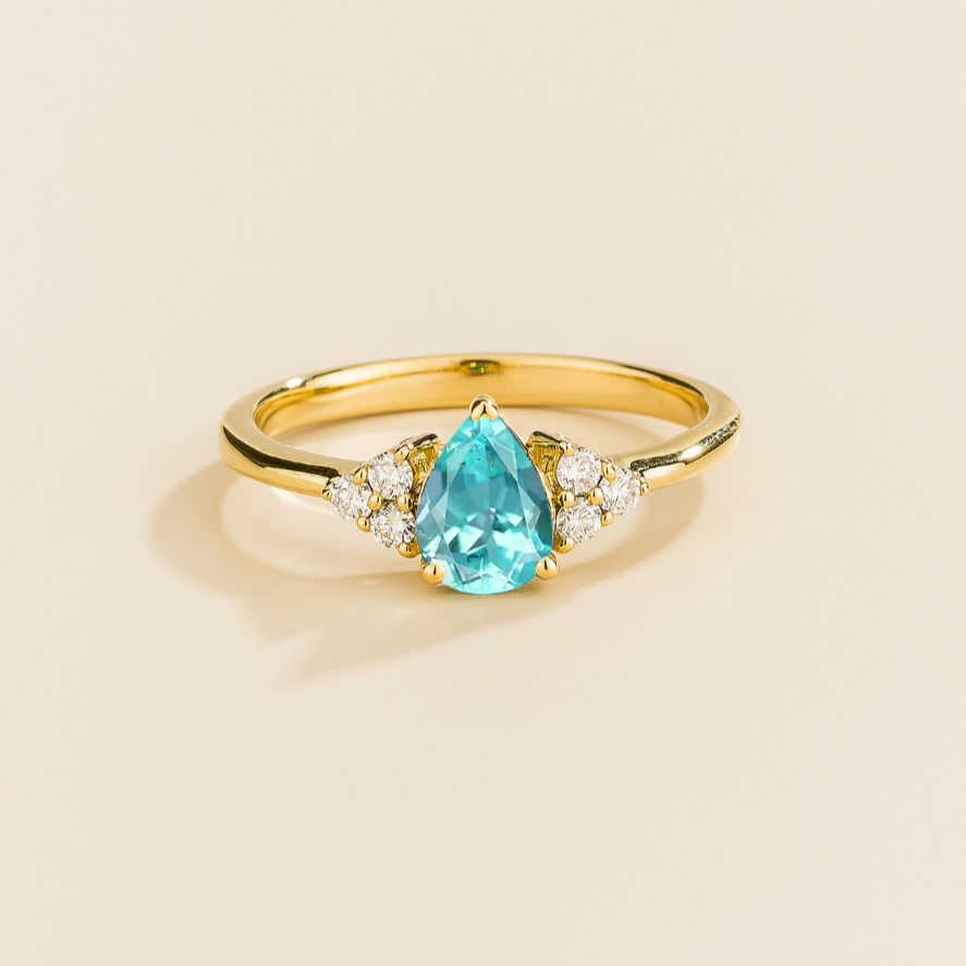 Juvetti yellow gold ring featuring a pear-cut lab-grown paraiba gemstone with lab-grown diamond side stones.