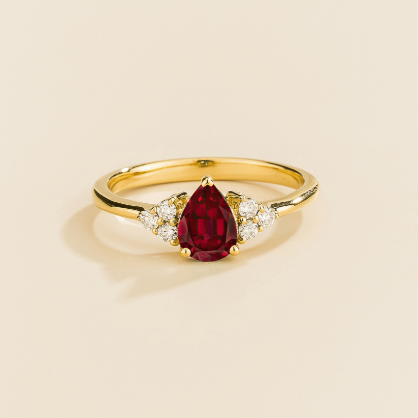Juvetti yellow gold ring featuring a pear-cut lab-grown ruby with lab-grown diamond side stones.