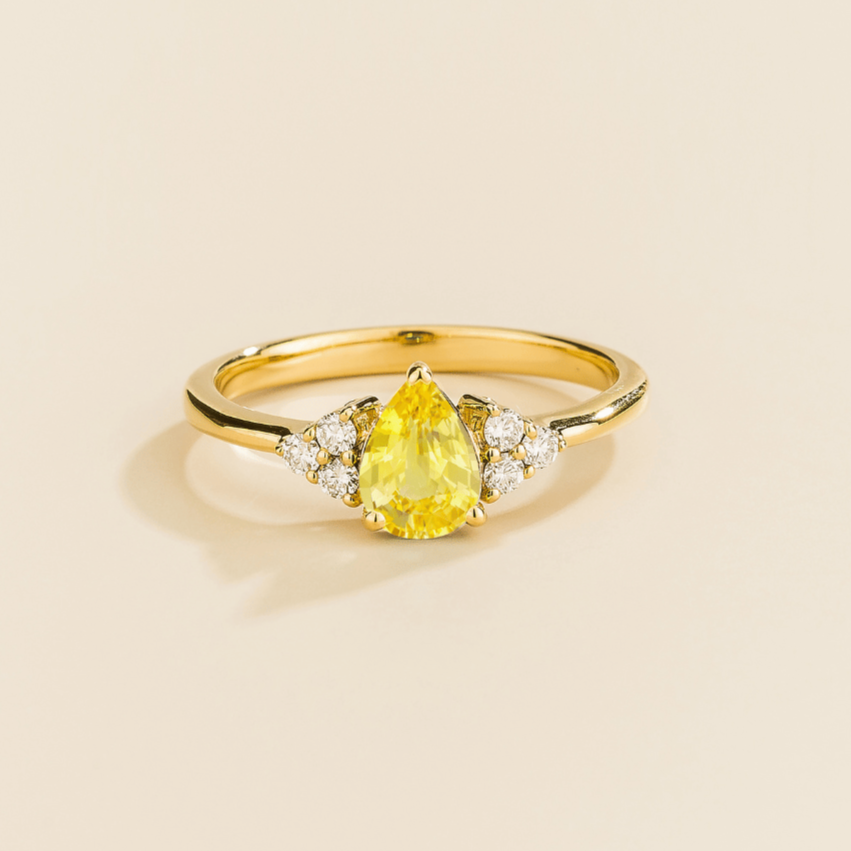 Juvetti yellow gold ring featuring a pear-cut lab-grown yellow sapphire with lab-grown diamond side stones.
