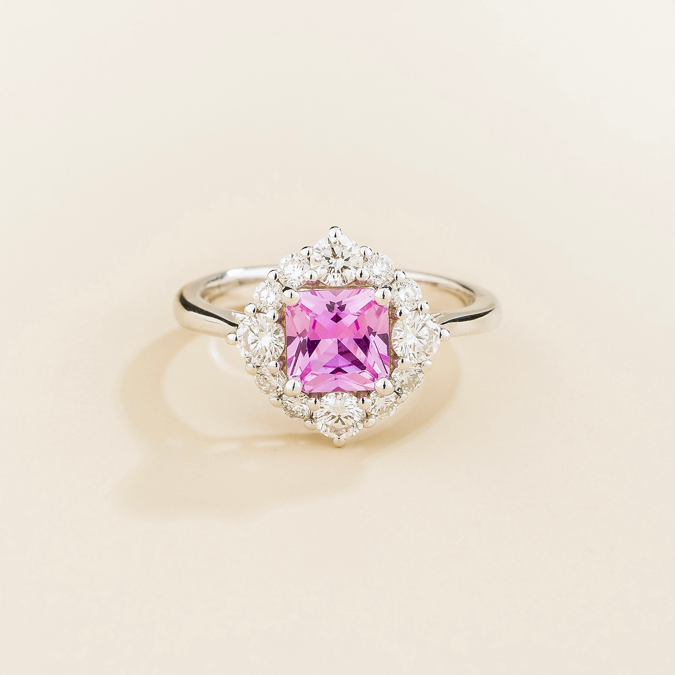 A white gold ring with a octagon cut pink sapphire center stone surrounded by smaller round diamonds.