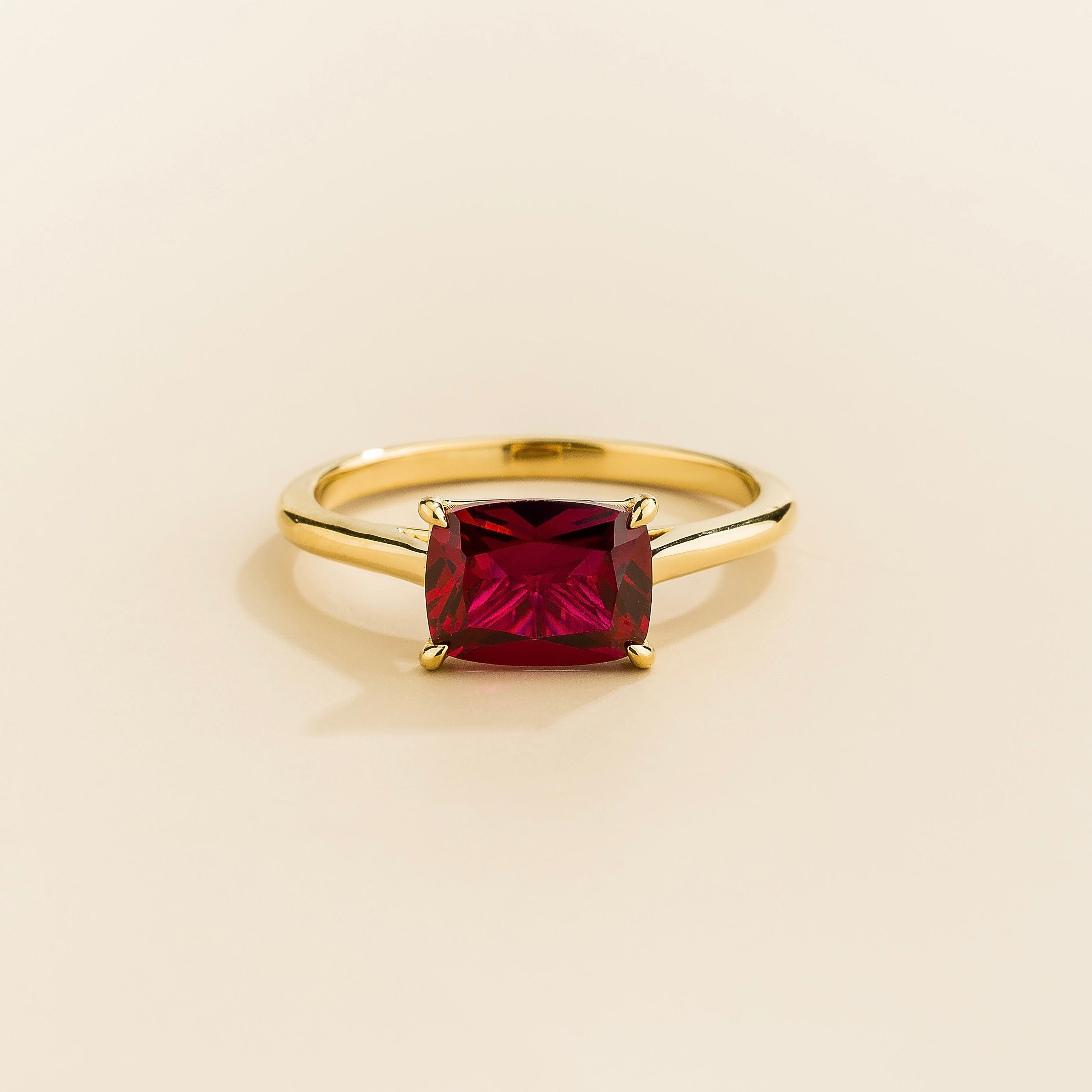 Juvetti yellow gold ring featuring a cushion-cut lab-grown ruby in an east–west setting.