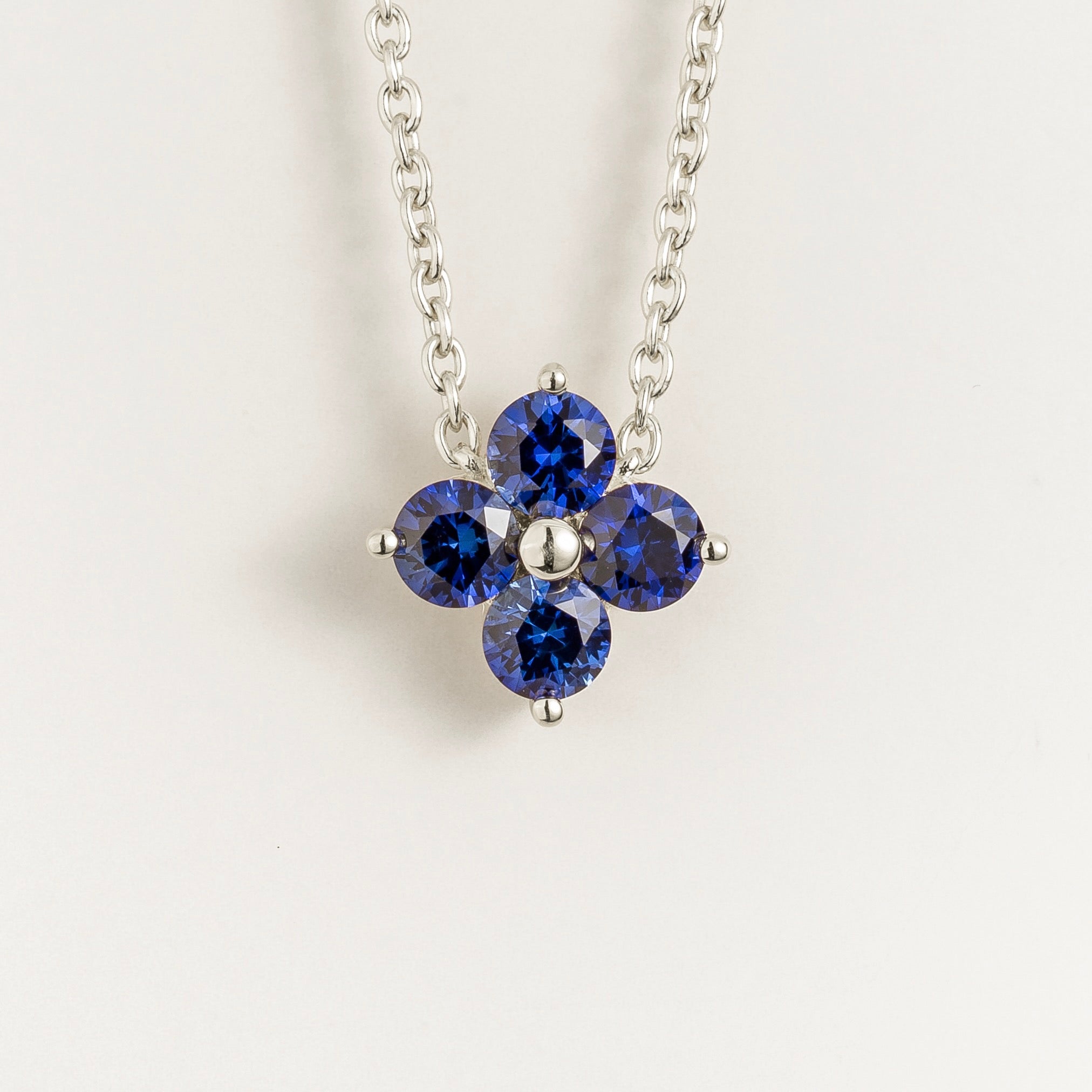 Juvetti white gold necklace featuring a clover pendant set with round lab-grown blue sapphires.