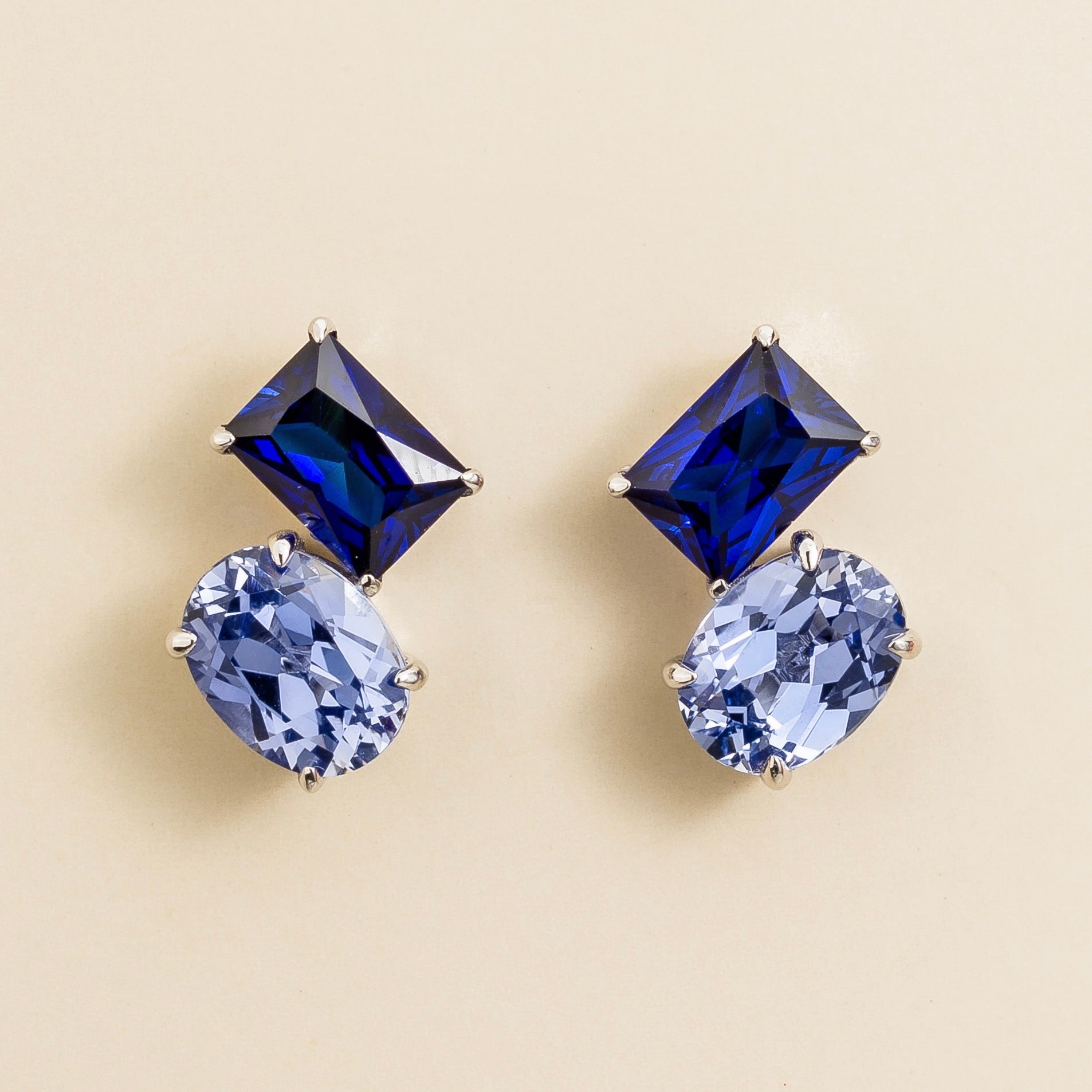 A pair of Toi et Moi white gold earrings featuring emerald royal blue sapphire cut and oval cut pastel blue sapphires. London jewellery store