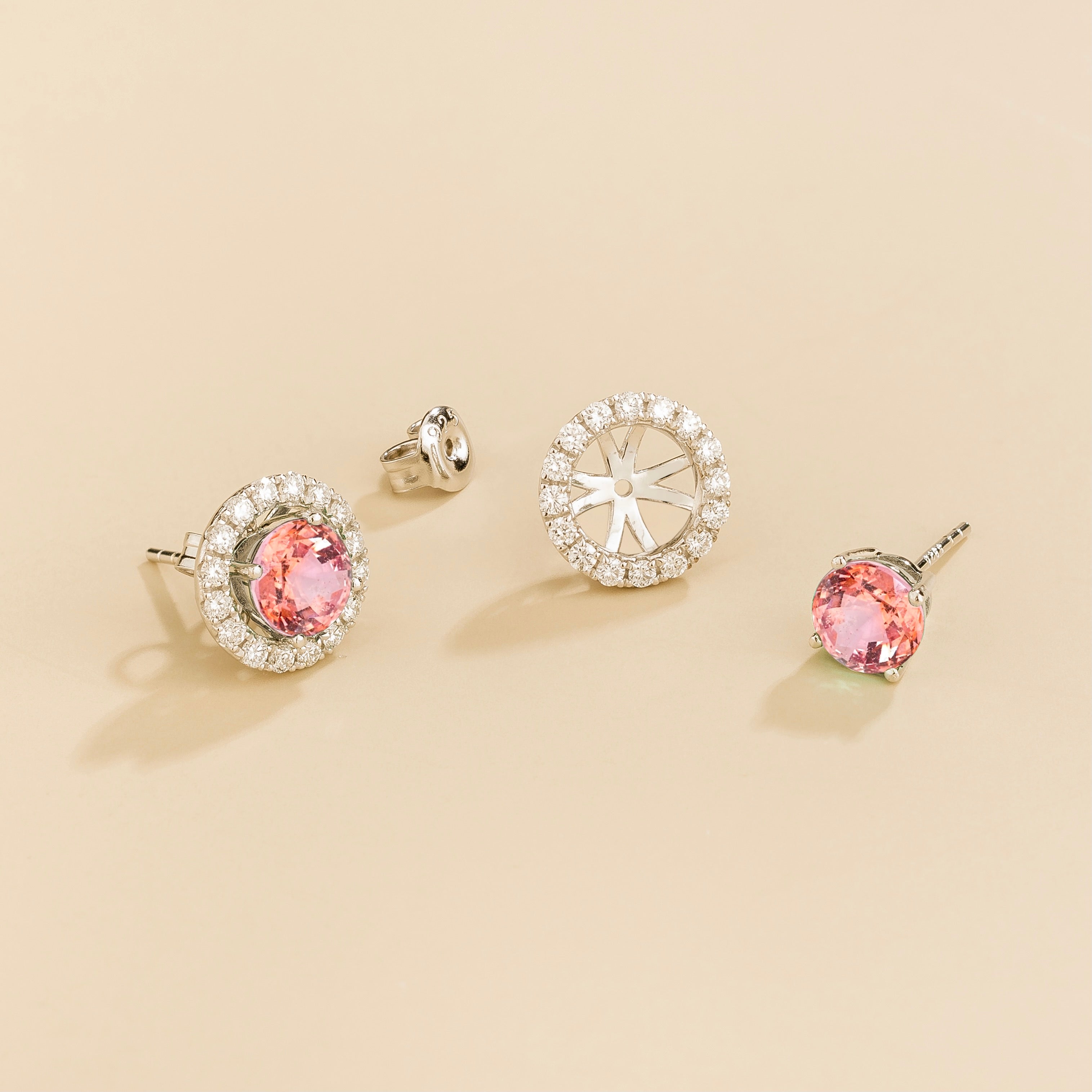 A pair of white gold floret earrings set with round padparadscha sapphire centerpiece and surrounding round diamonds halo. Removable halo piece.