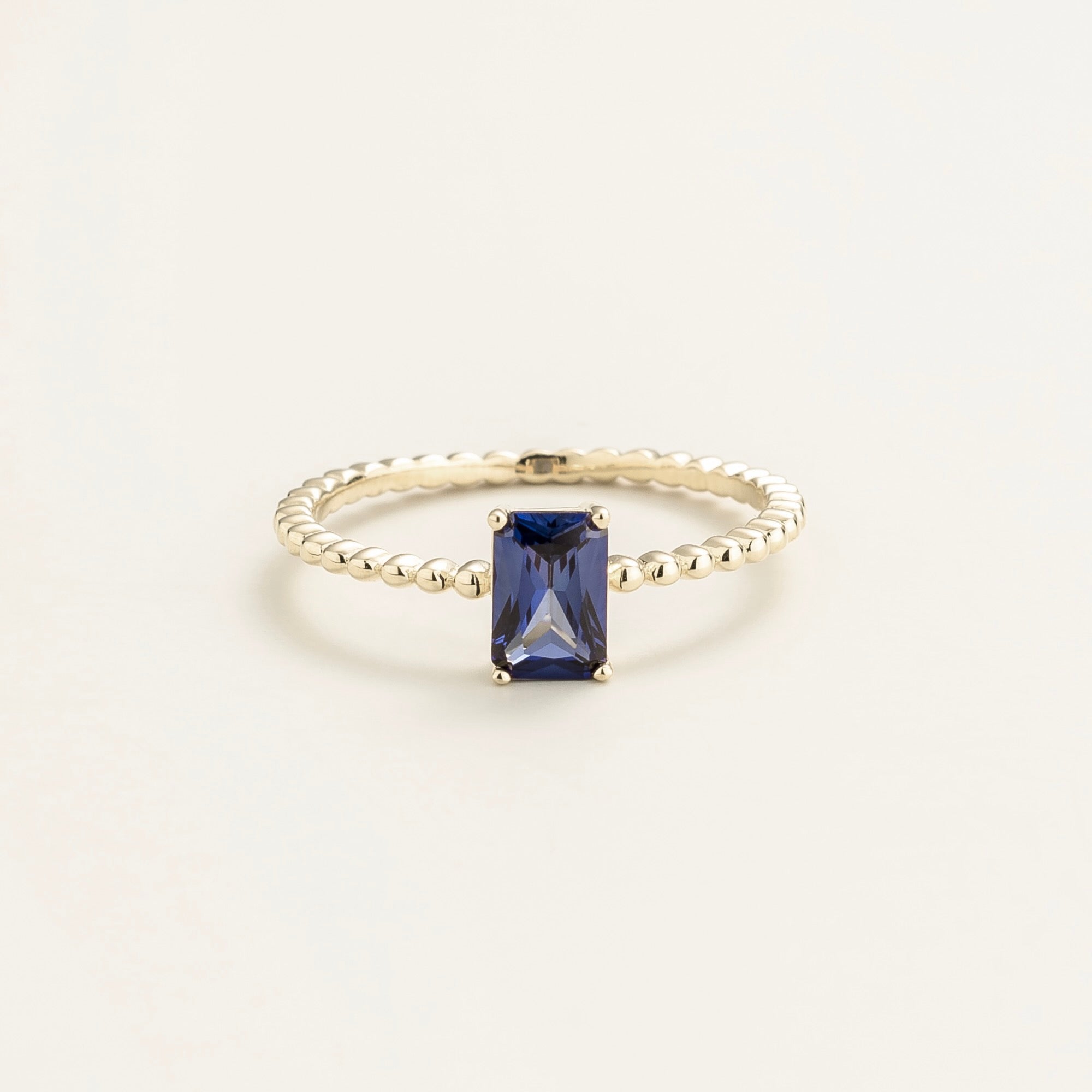 Juvetti white gold ring featuring an emerald-cut lab-grown royal blue sapphire on a beaded band.