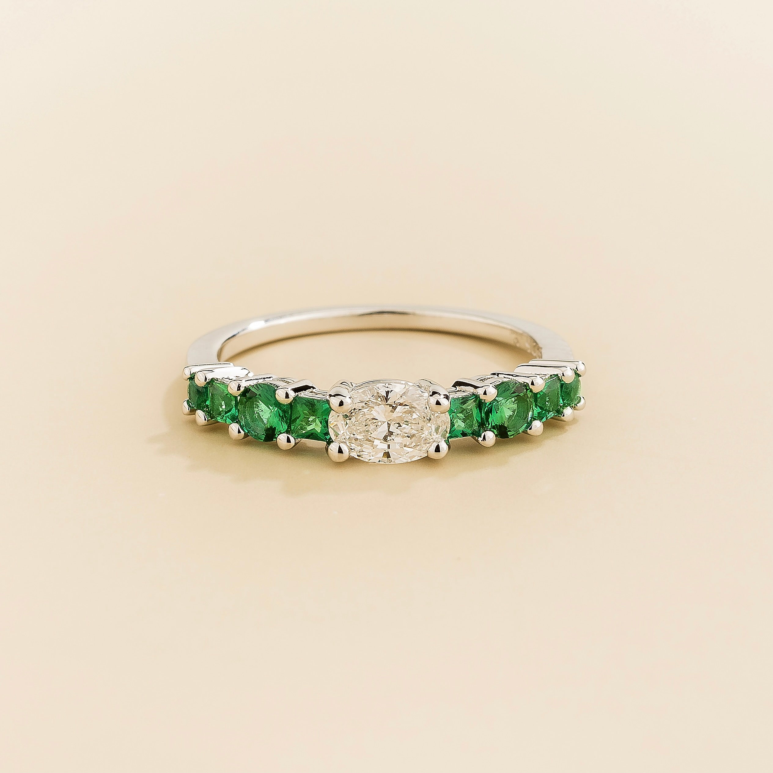 Juvetti white gold ring featuring a round lab-grown diamond centre stone with vivid green lab-grown emerald side stones.