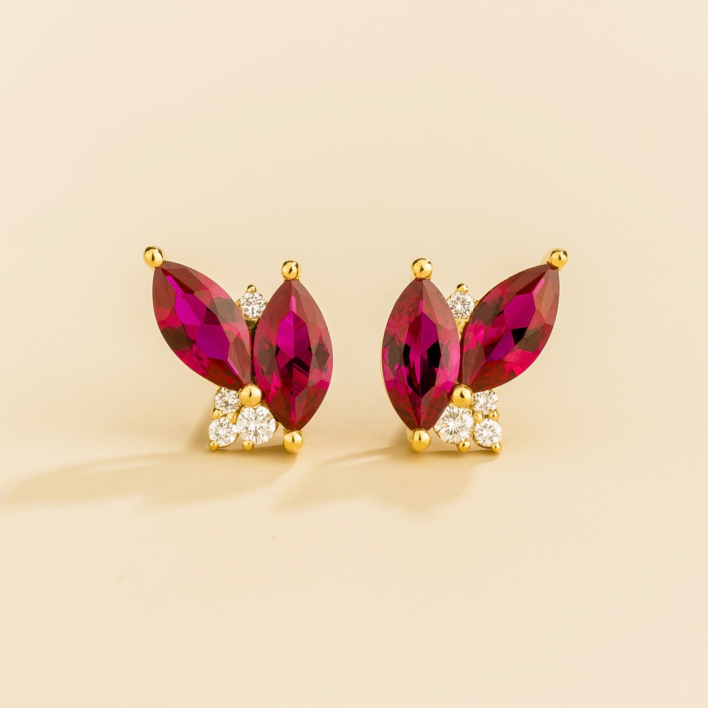 A pair of Vento gold earrings with marquis ruby and round diamond embellishments.