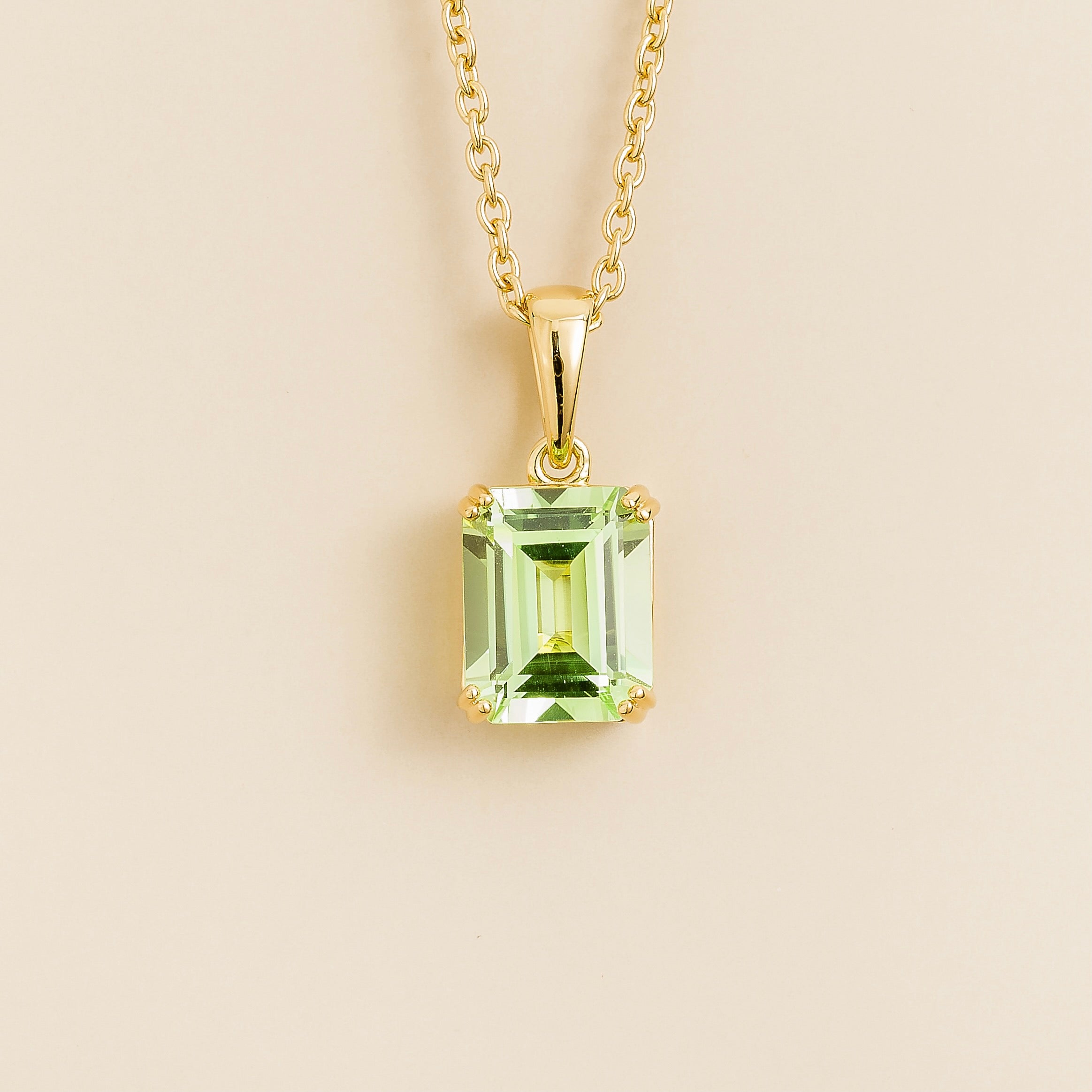 A gold pendant necklace with an emerald-cut green sapphire centerpiece. London jewellery store