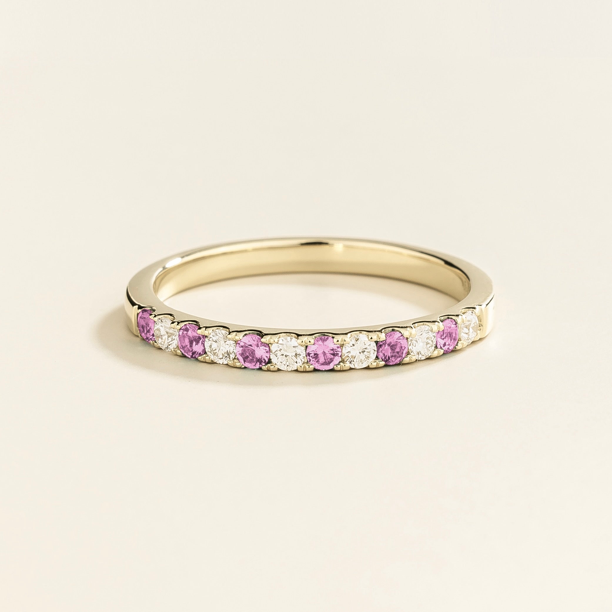 A white gold half eternity ring with pastel pink sapphire and diamonds set in an alternating pattern.