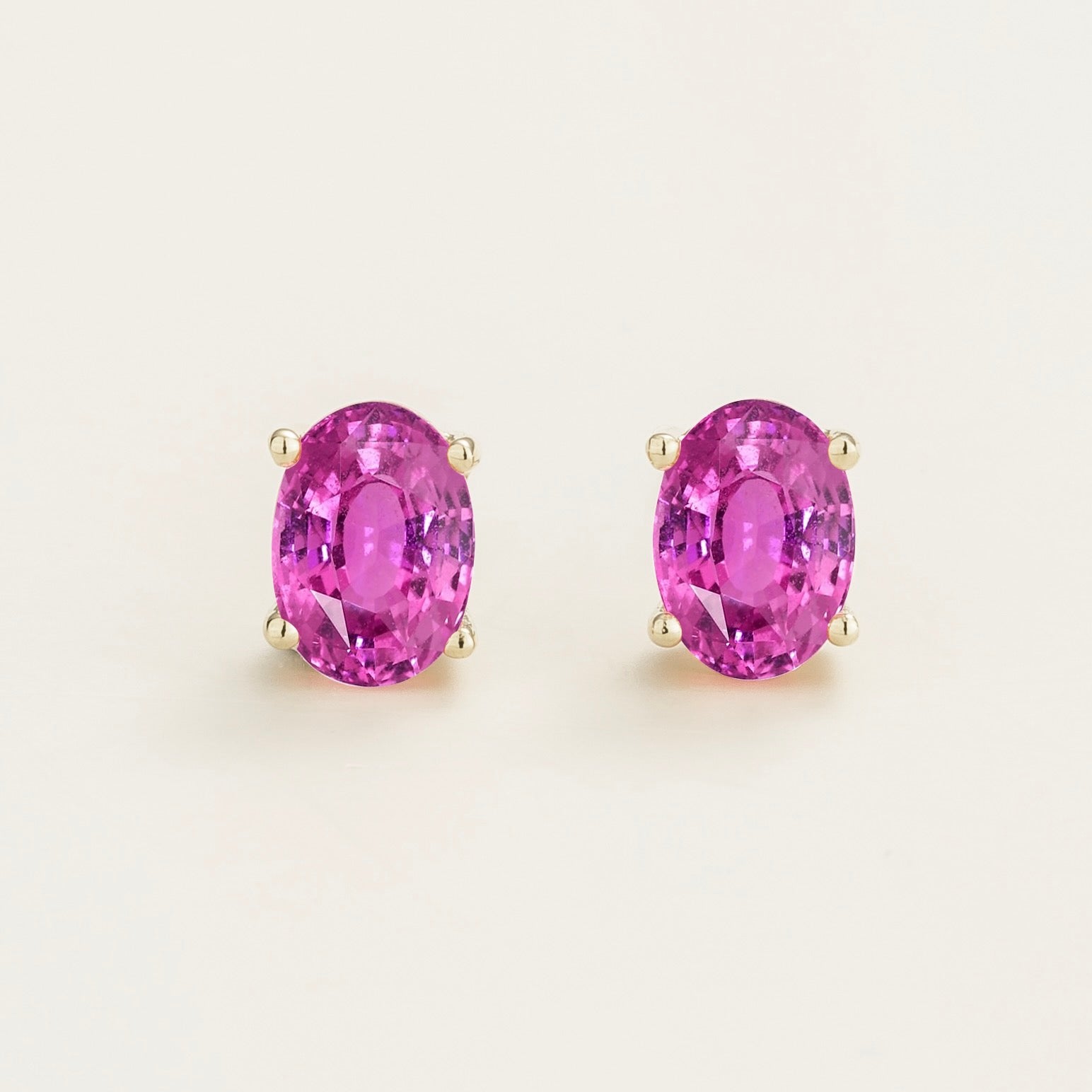 Yellow gold stud earrings with oval pink sapphire gemstones in four-prong setting