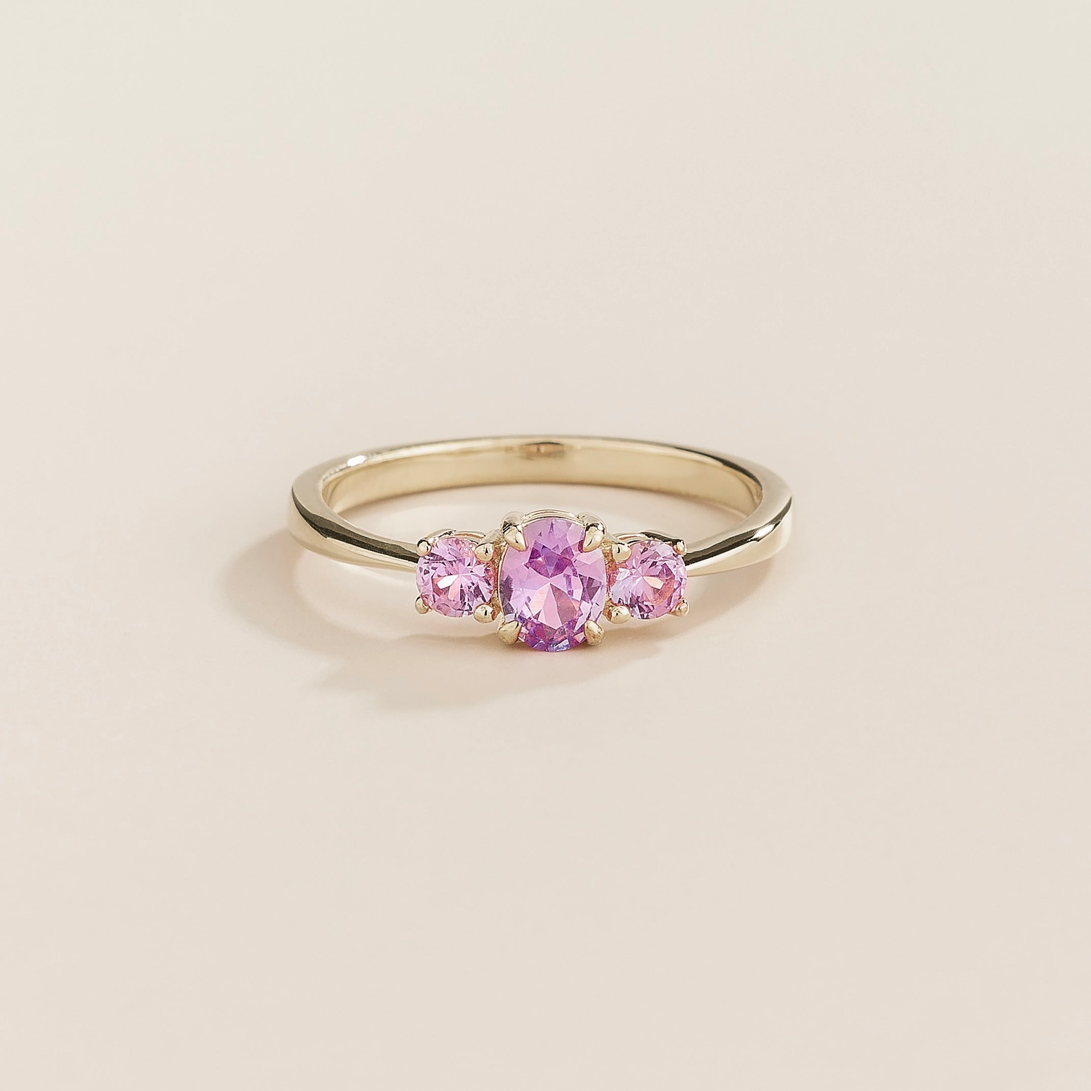 A white gold ring set with three purple sapphire gemstones, with a simplistic and elegant band.