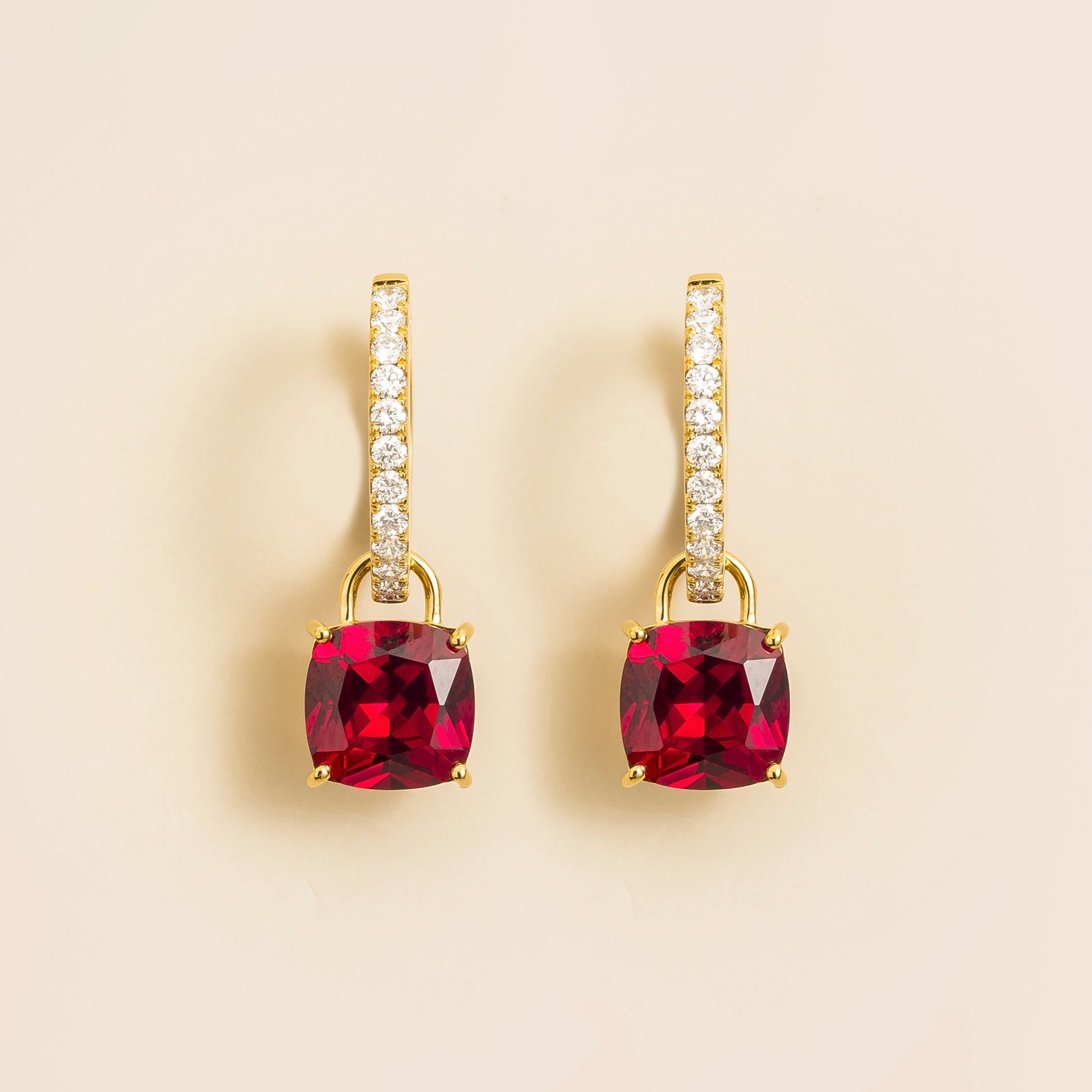 A pair of Oreol drop earrings in gold, featuring cushion-cut rubies and smaller diamond huggie arranged in a hoop design.
