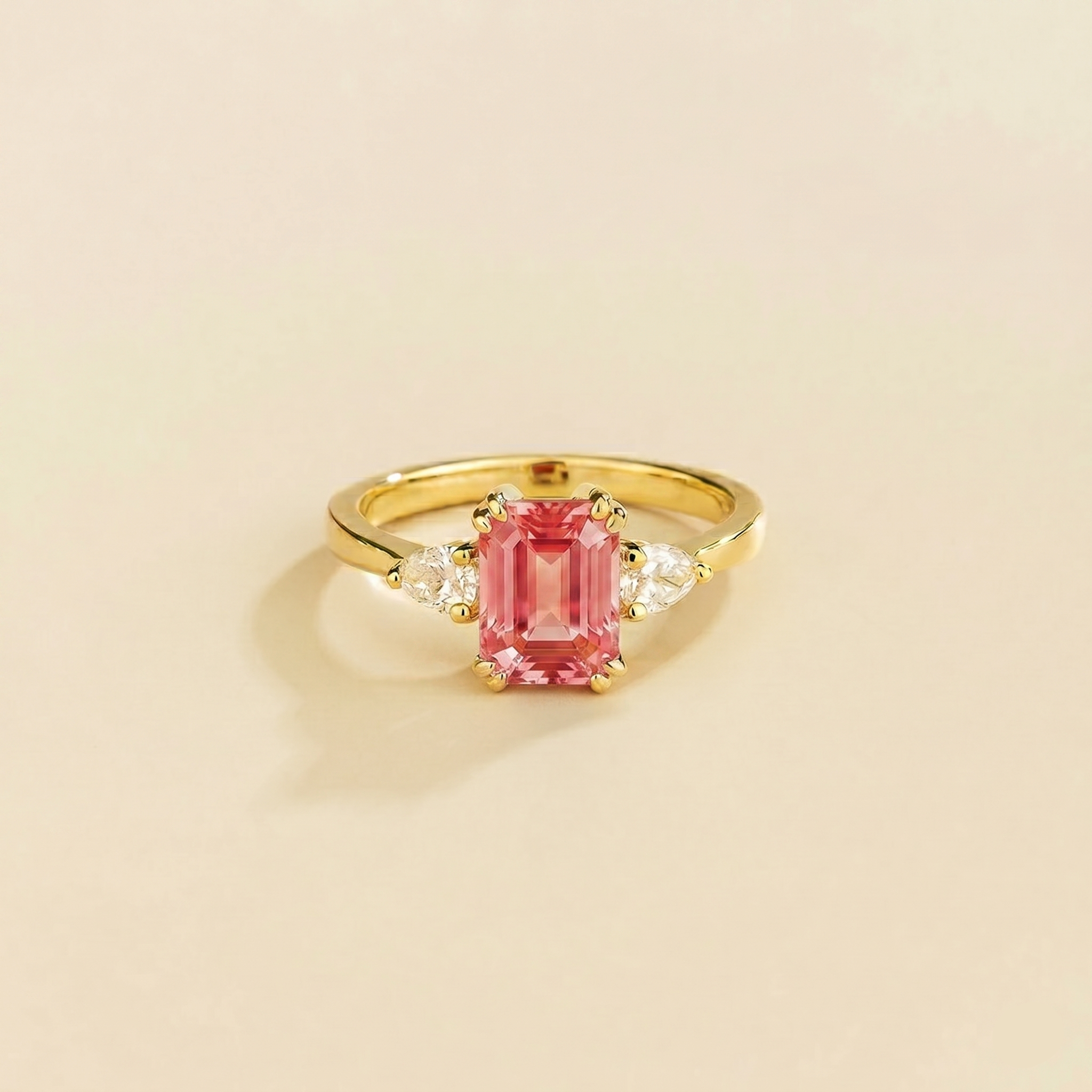 Emerald-cut lab-grown padparadscha sapphire ring with pear-cut diamond sides, Ailes design in gold | Juvetti London