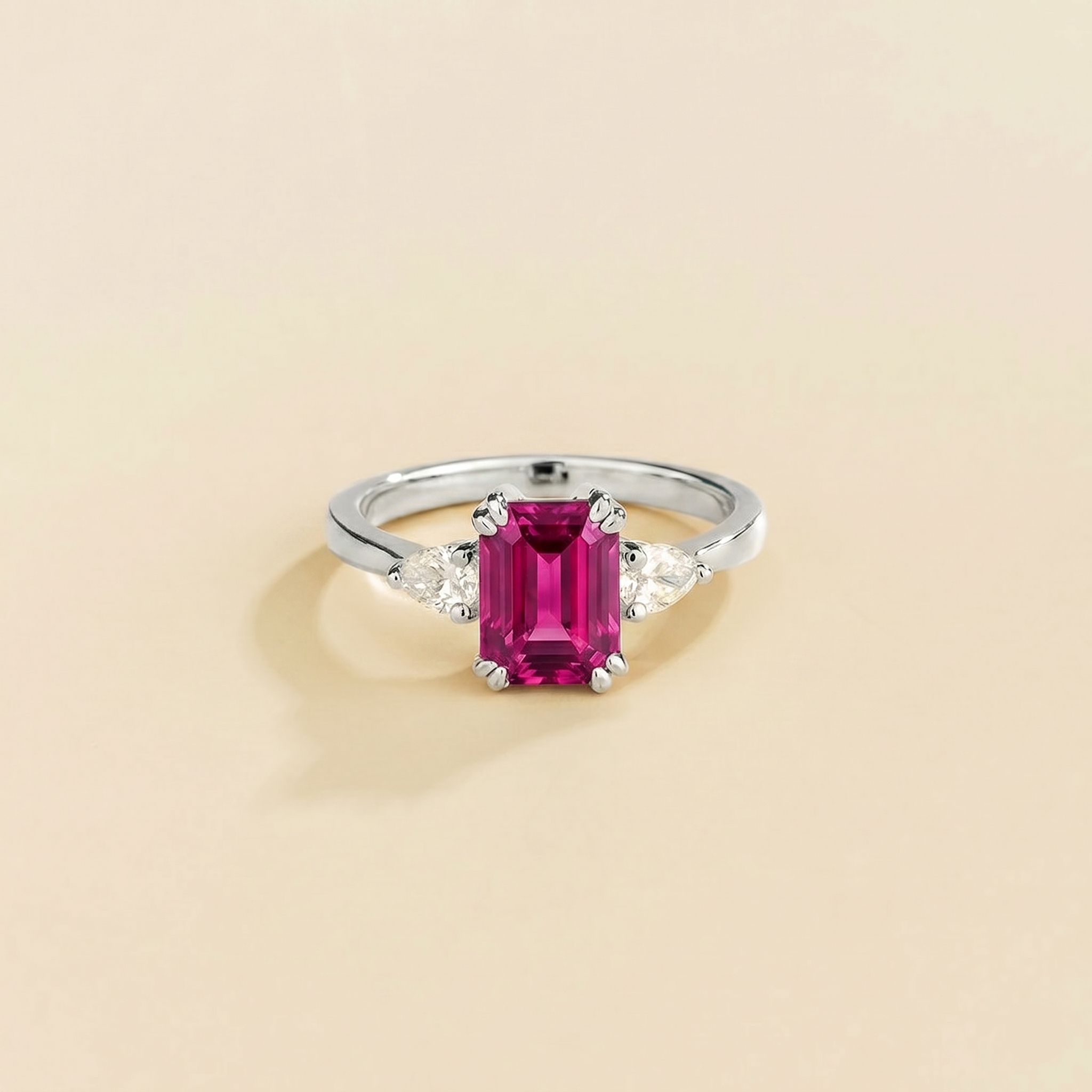 Emerald-cut lab-grown vivid pink sapphire ring with pear-cut diamond sides, Ailes design in white gold | Juvetti London
