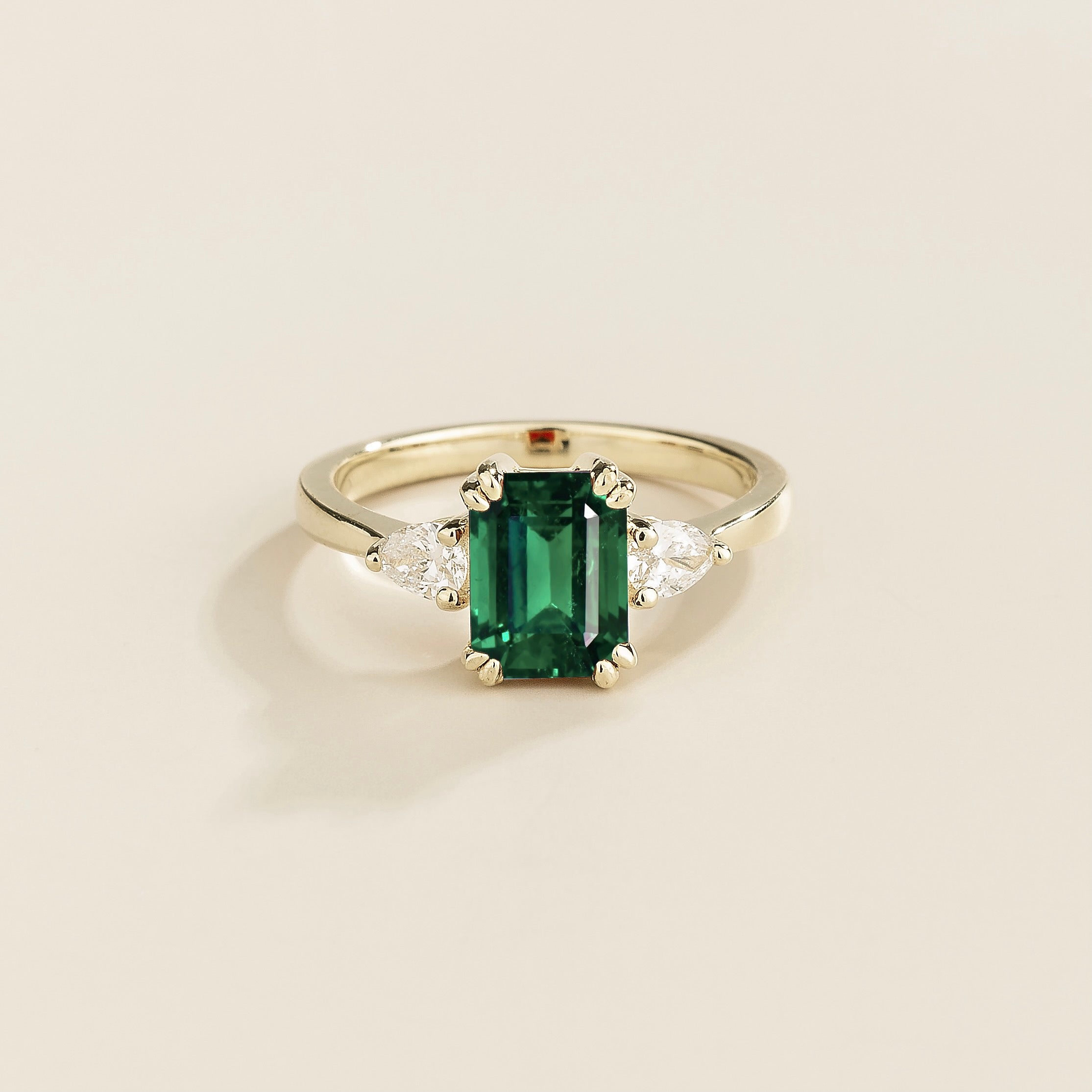 A white gold ring with a emerald cut gemstone and pear diamonds set in the band.