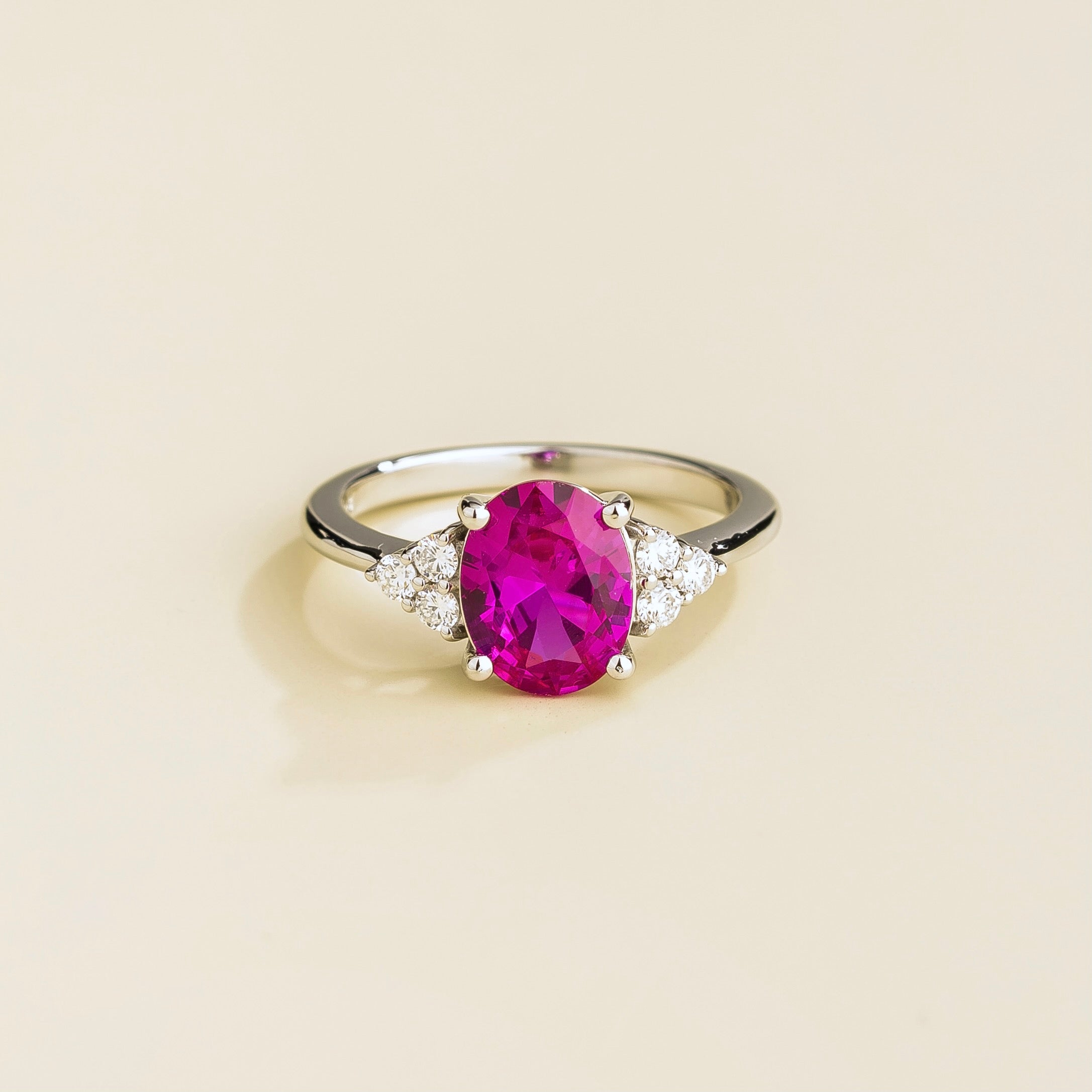A white gold ring with an oval pink sapphire center stone and smaller diamonds accent