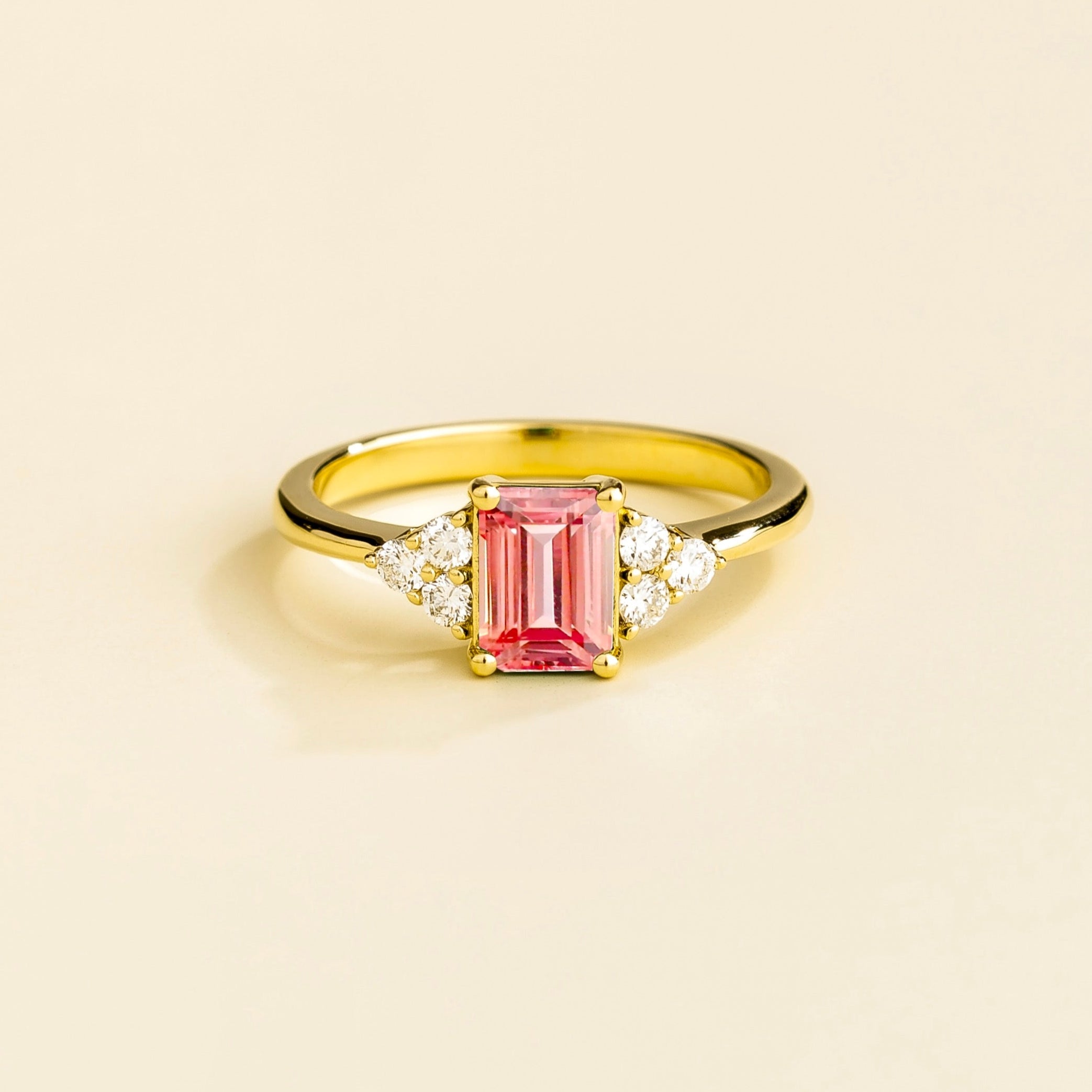 Juvetti yellow gold ring featuring an emerald-cut lab-grown padparadscha sapphire with lab-grown diamond side stones.