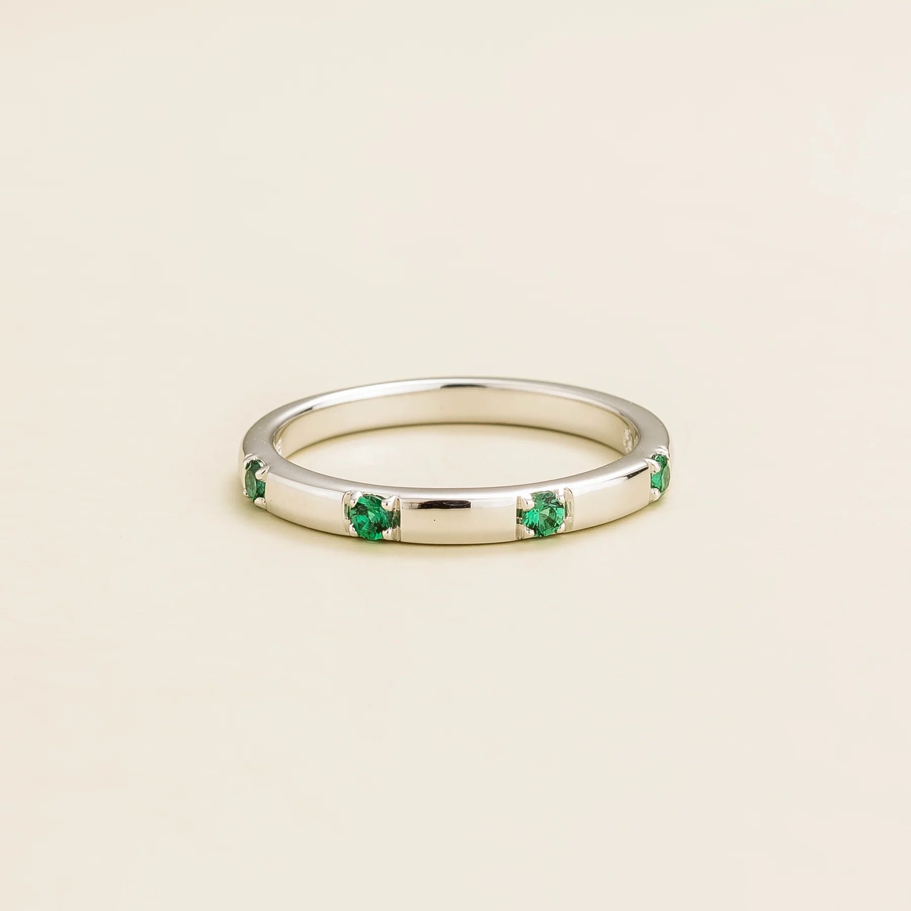 Juvetti white gold band set with round lab-grown emerald in a sleek modern design.London