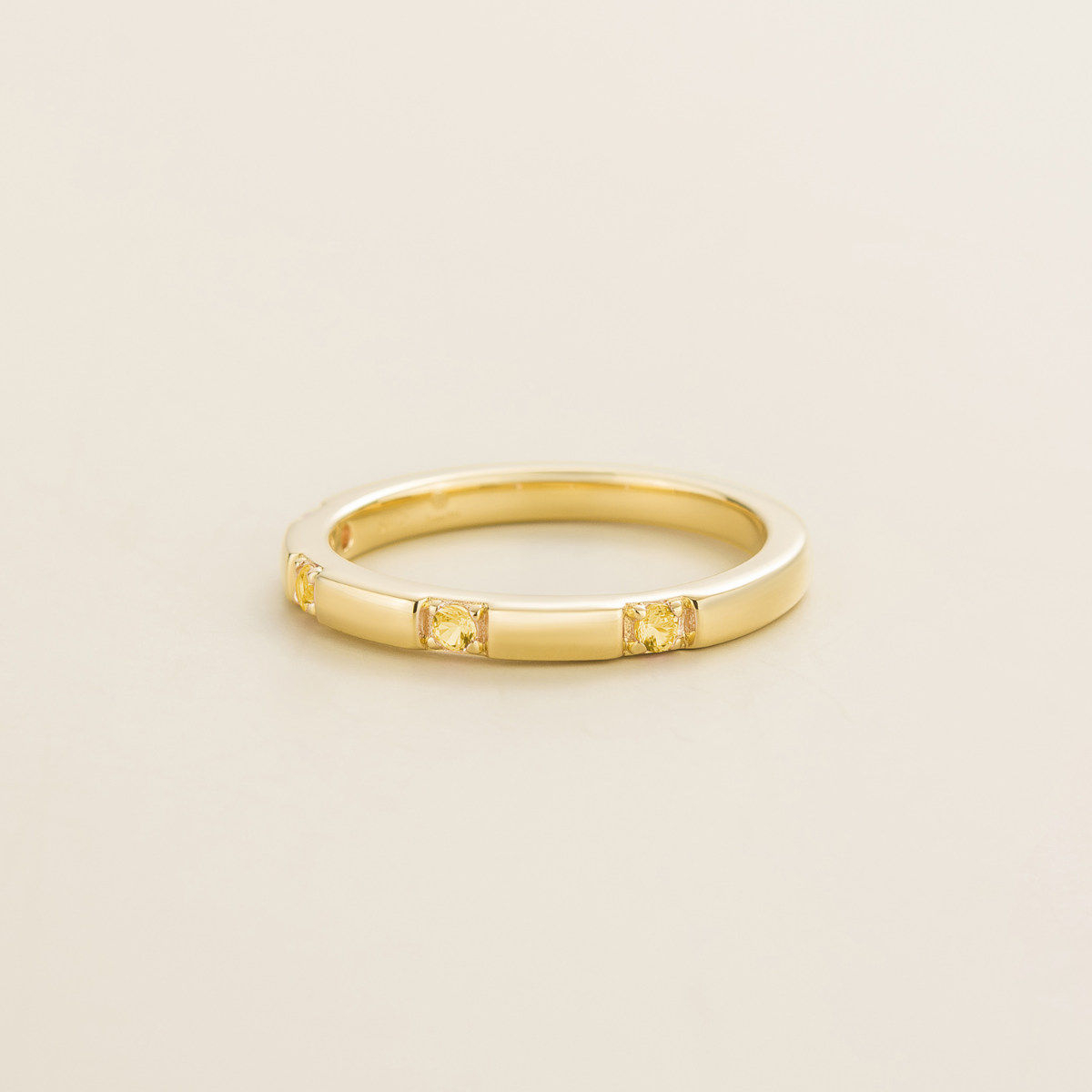 Juvetti yellow gold band set with round lab-grown yellow sapphire gemstones in a sleek modern design.