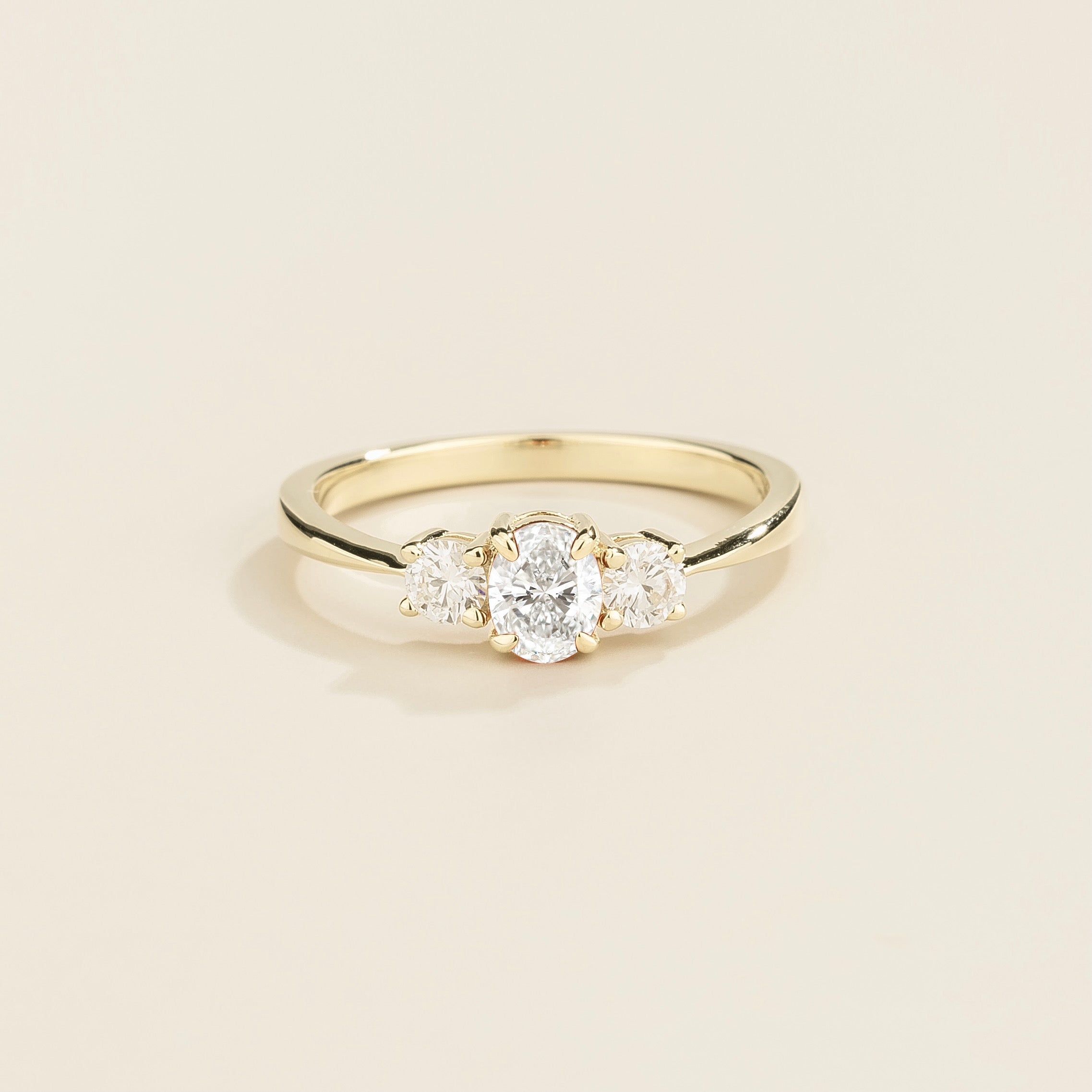 3 gemstones white gold ring featuring a central diamond with two smaller diamonds on either side, set against a plain background.