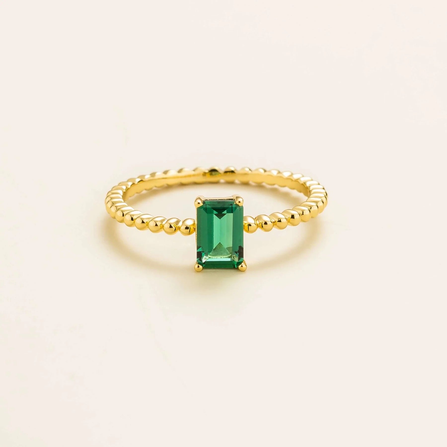 Juvetti gold ring featuring an emerald-cut lab-grown emerald on a beaded band.