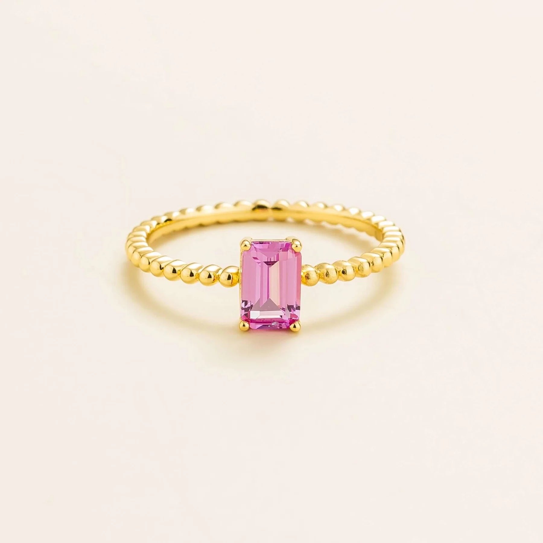 Juvetti gold ring featuring an emerald-cut lab-grown pink sapphire on a beaded band.