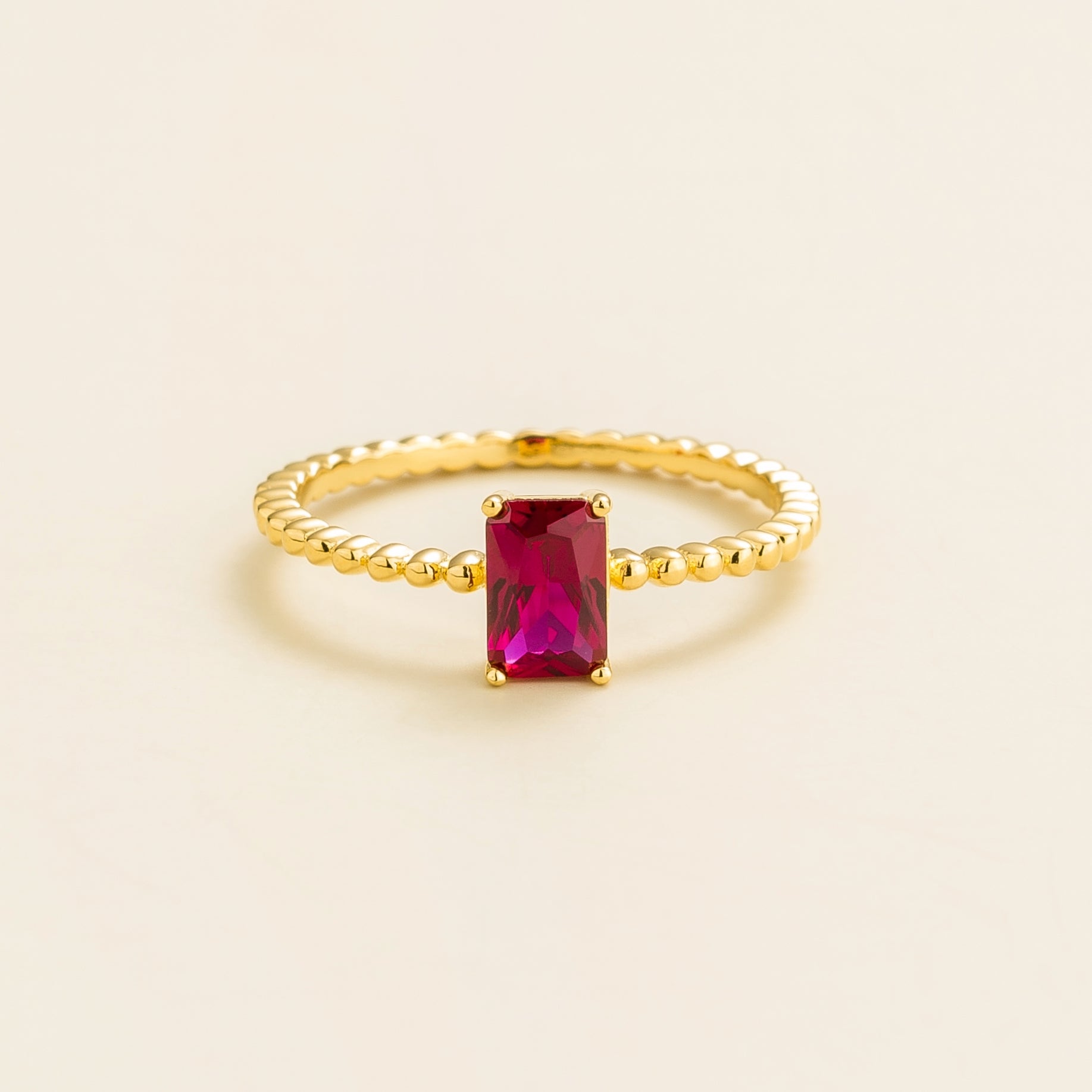 Juvetti gold ring featuring an emerald-cut lab-grown ruby on a beaded band.