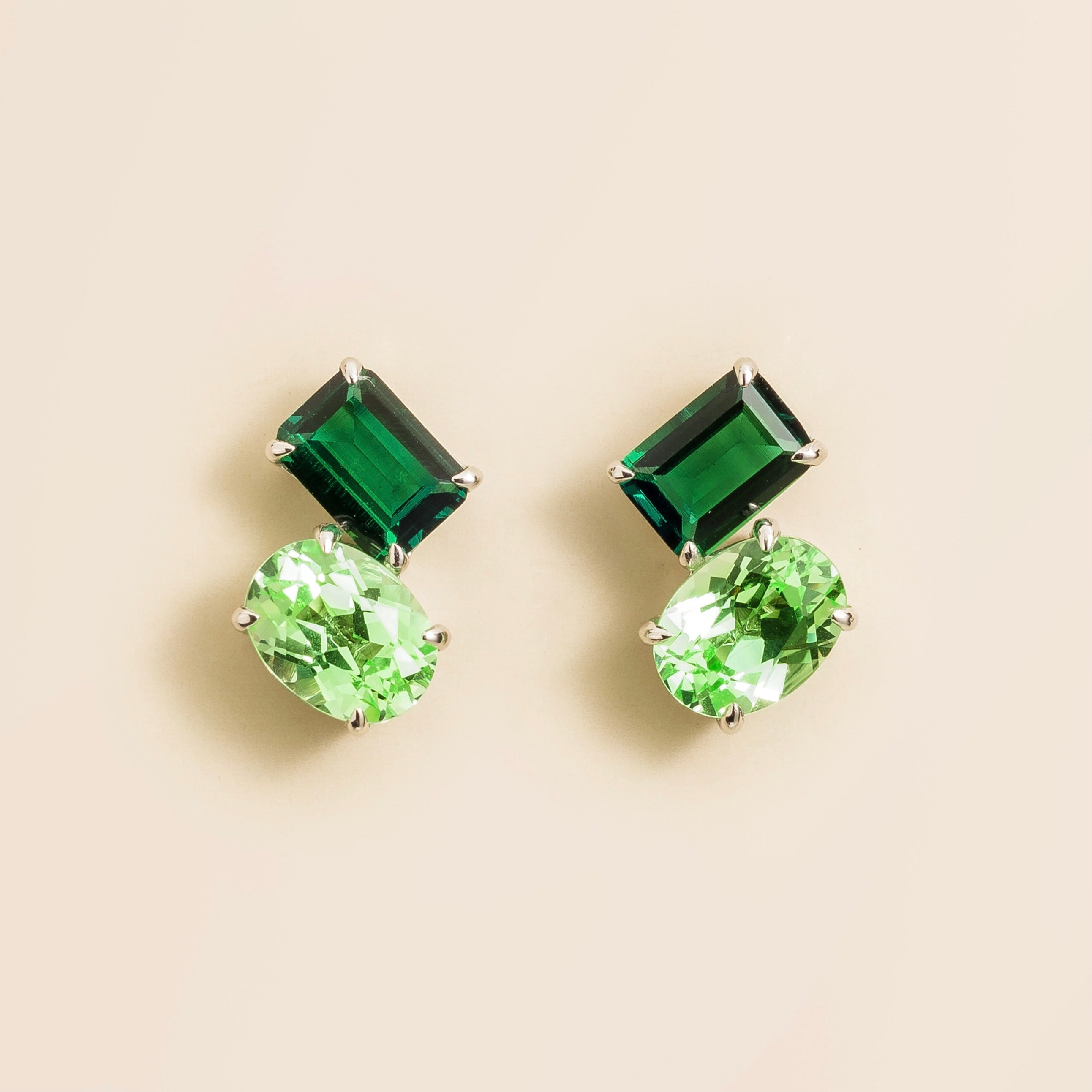 A pair of white gold earrings set with emerald cut emerald and oval cut green sapphire. London jewellery store