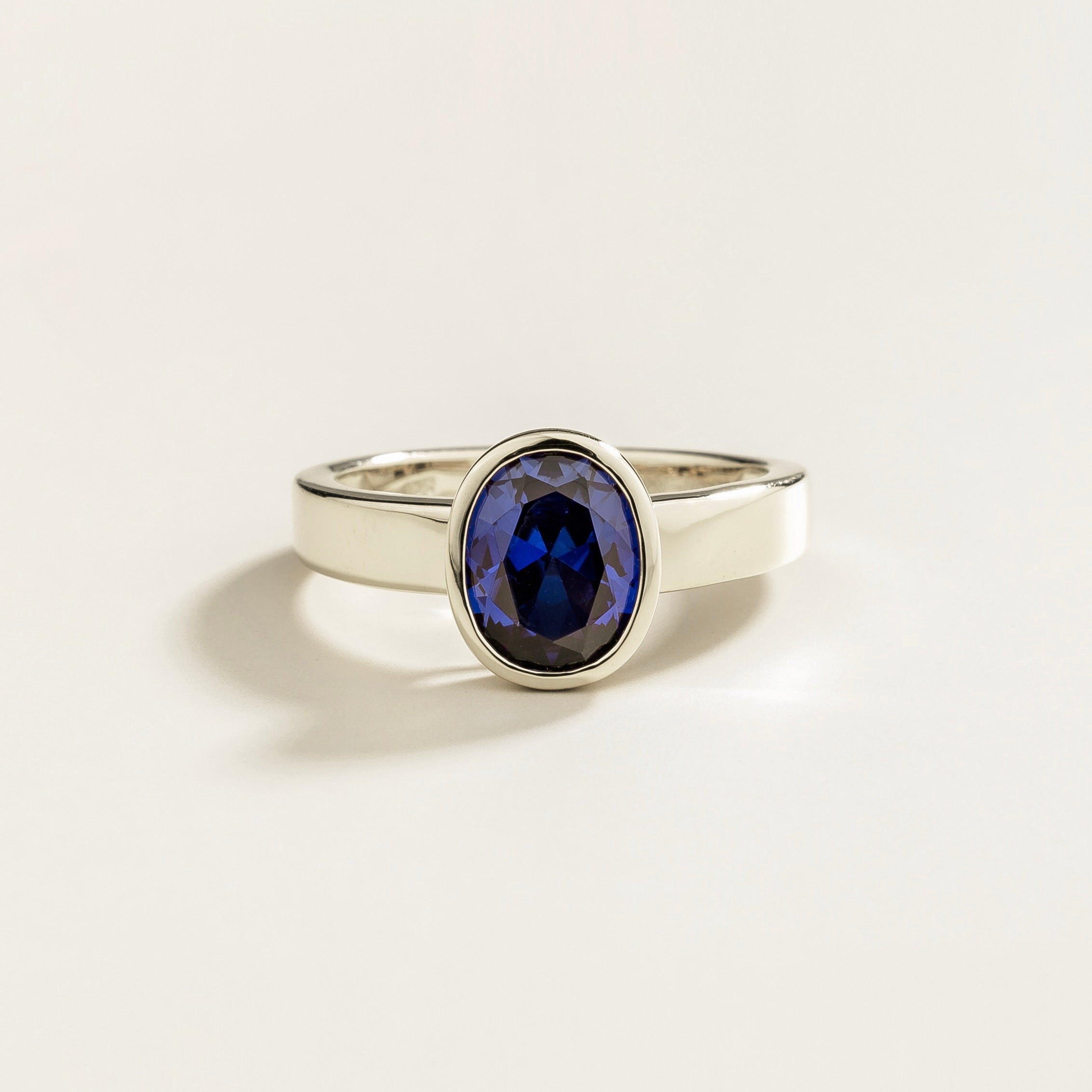 Juvetti white gold ring featuring an oval lab-grown blue sapphire in a bezel setting.