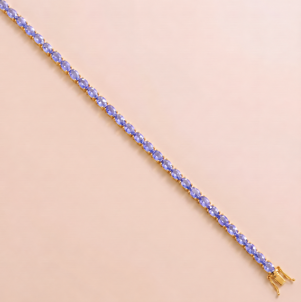 A gold tennis bracelet set with oval light blue sapphire gemstones.