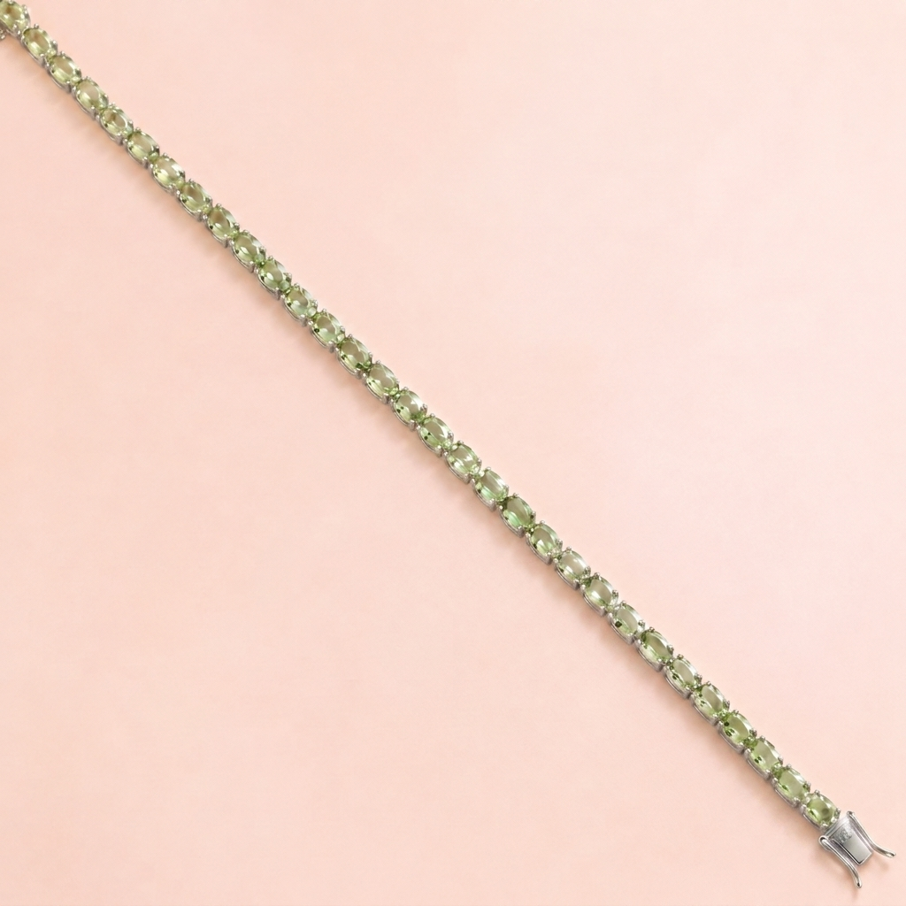 A white gold tennis bracelet set with oval green sapphire gemstones.