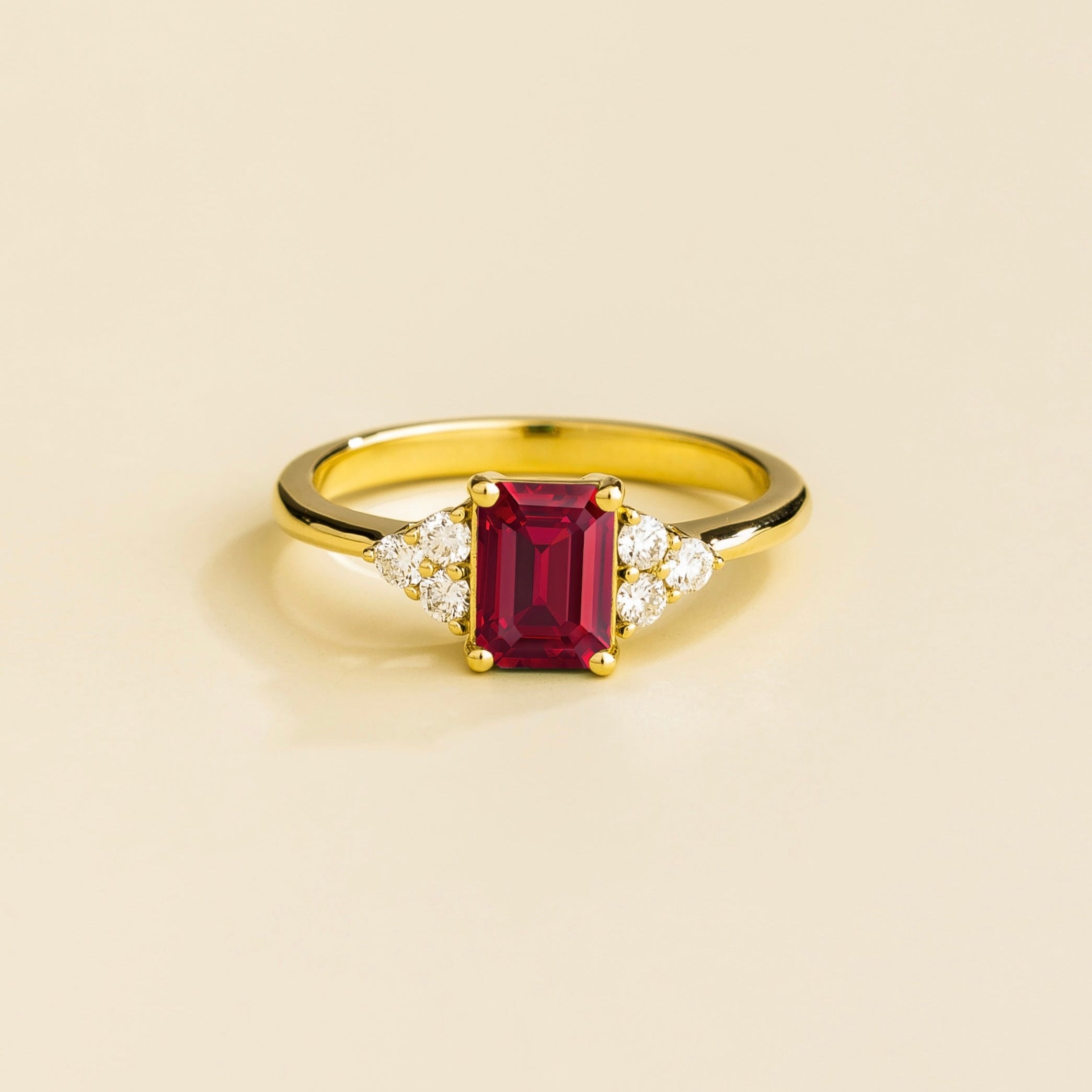 Juvetti yellow gold ring featuring an emerald-cut lab-grown ruby with lab-grown diamond side stones.