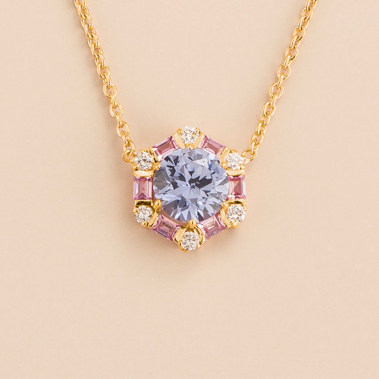 A gold necklace with a hexagon-shaped pastel blue sapphire centerpiece, surrounded by baguette cut pink sapphires and round diamonds. London jewellery store