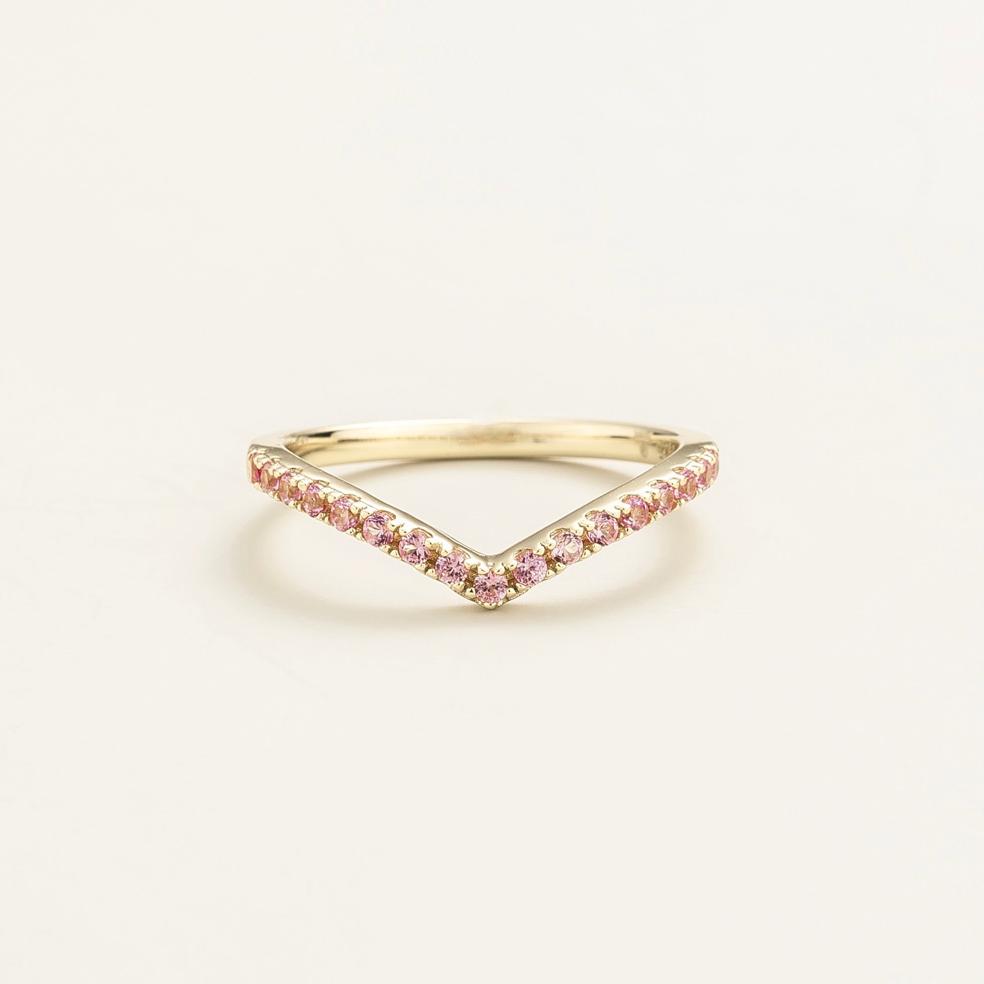A white gold chevron ring with pink sapphires set in a V-shaped design.