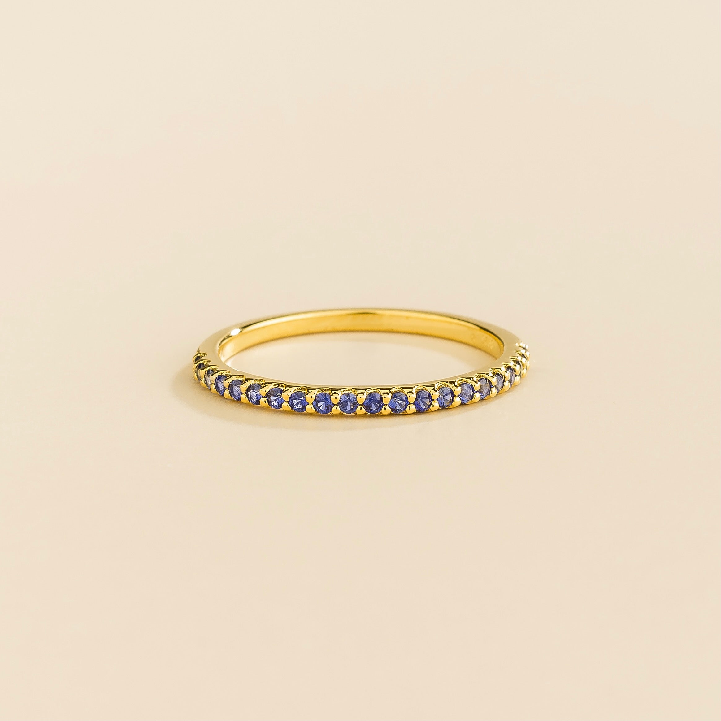 Juvetti yellow gold half eternity band set with round lab-grown blue sapphire gemstones.