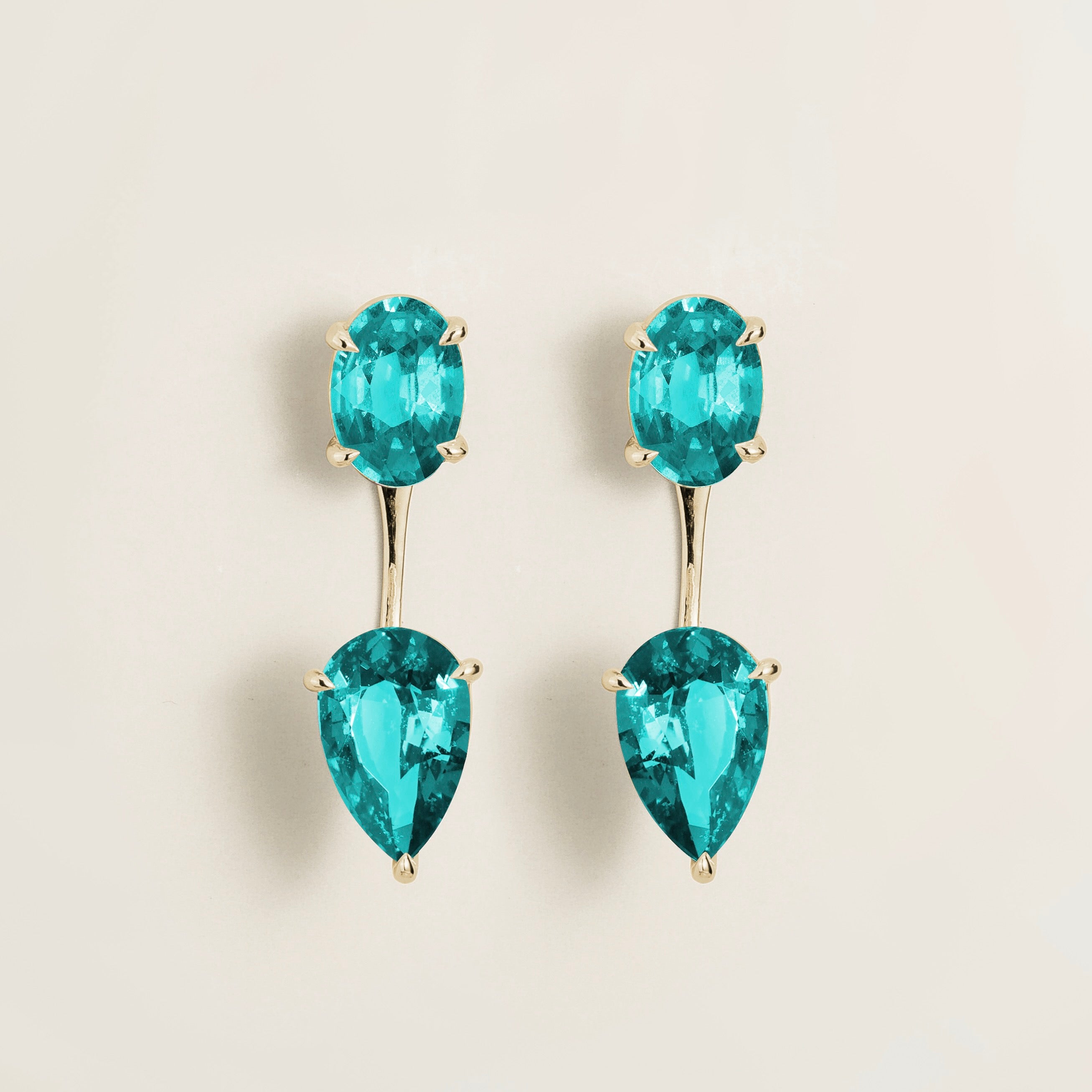 A pair of white gold earrings featuring oval shaped Paraiba sapphires with a detachable three-step pear drop design.