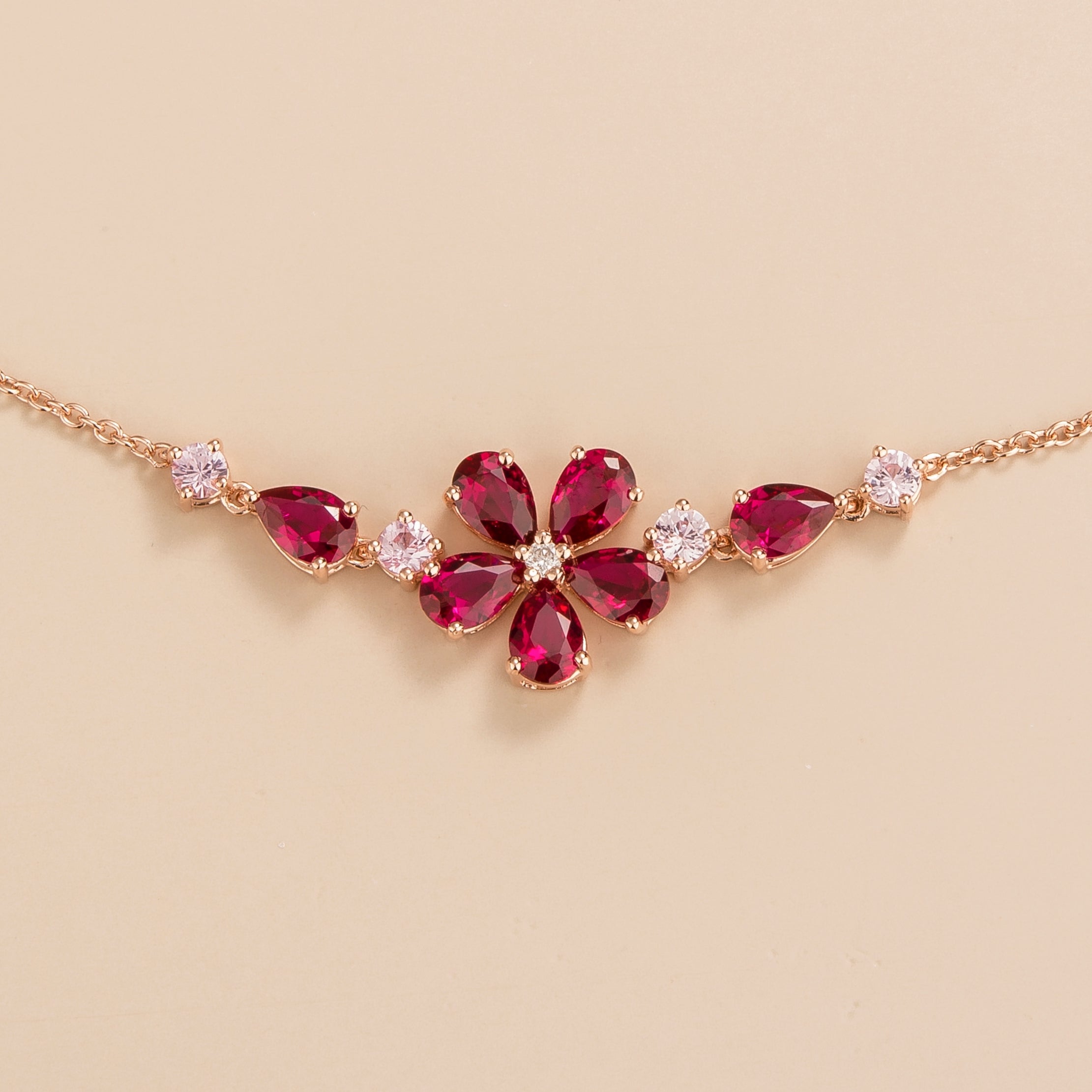 A rose gold necklace with a floral design, featuring pear-shaped rubies, round pink sapphires, and round diamonds set in a cluster. Best Online Jewellery London UK