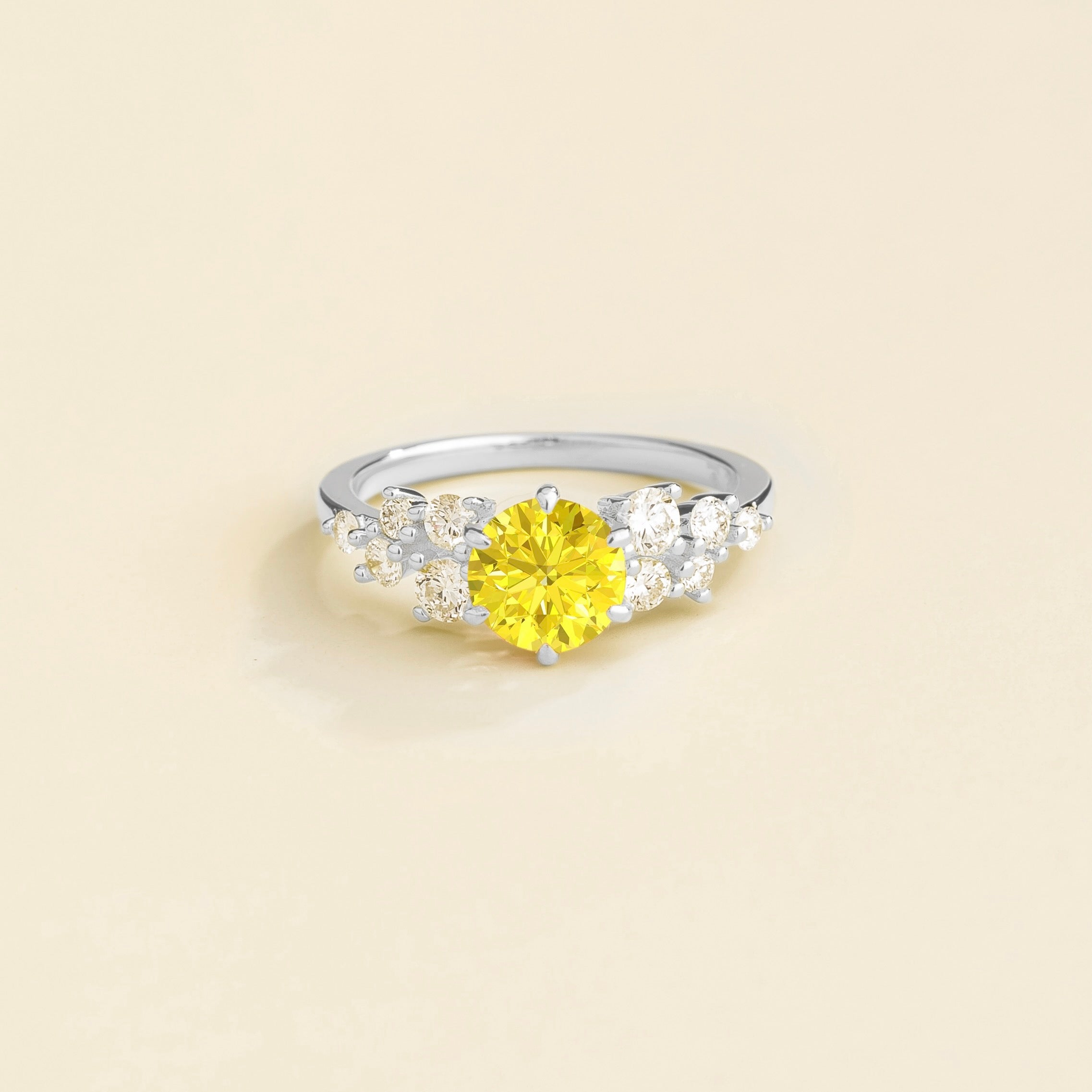 A white gold ring with a yellow sapphire center stone and smaller diamonds cluster set in gold, displayed against a neutral background.