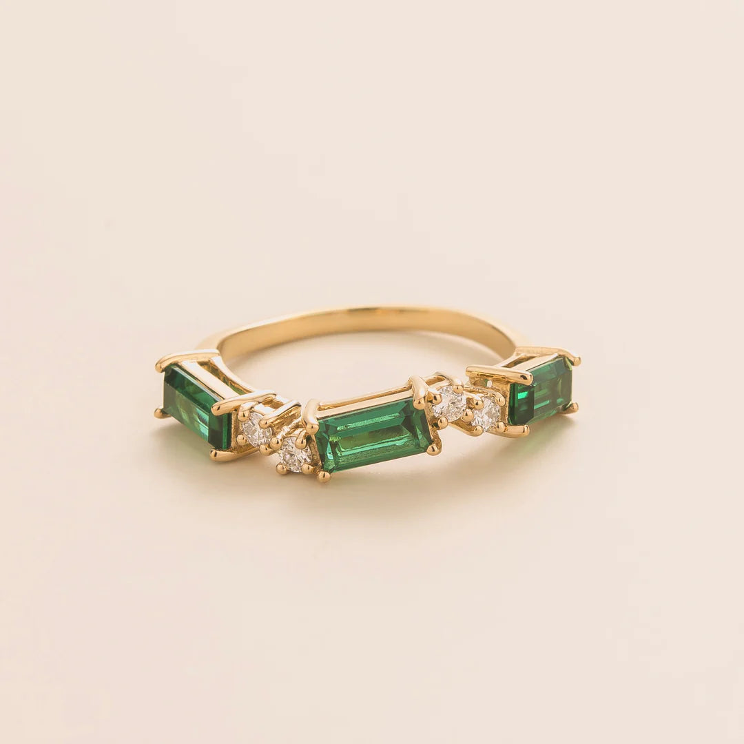 Juvetti gold ring showcasing ethical lab-grown baguette-cut emeralds and round brilliant diamonds.